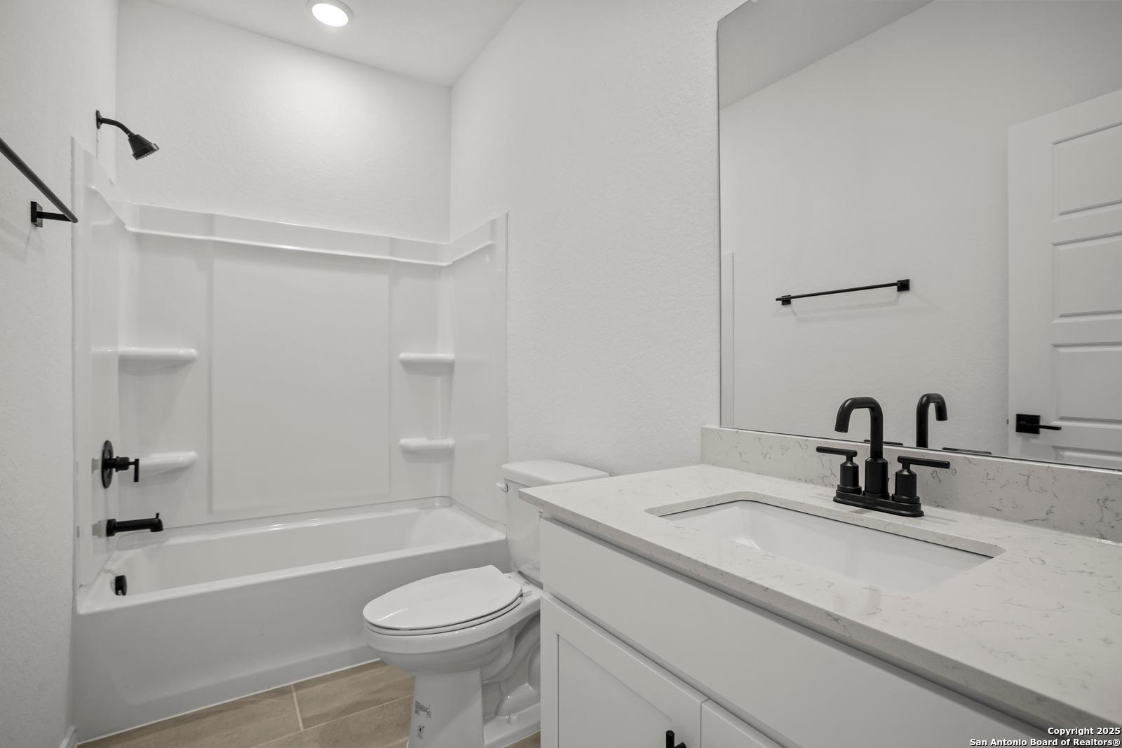 Modern white bathroom with quartz vanity, deep tub, walk-in shower in Davidson Homes The Daphne K, San Antonio