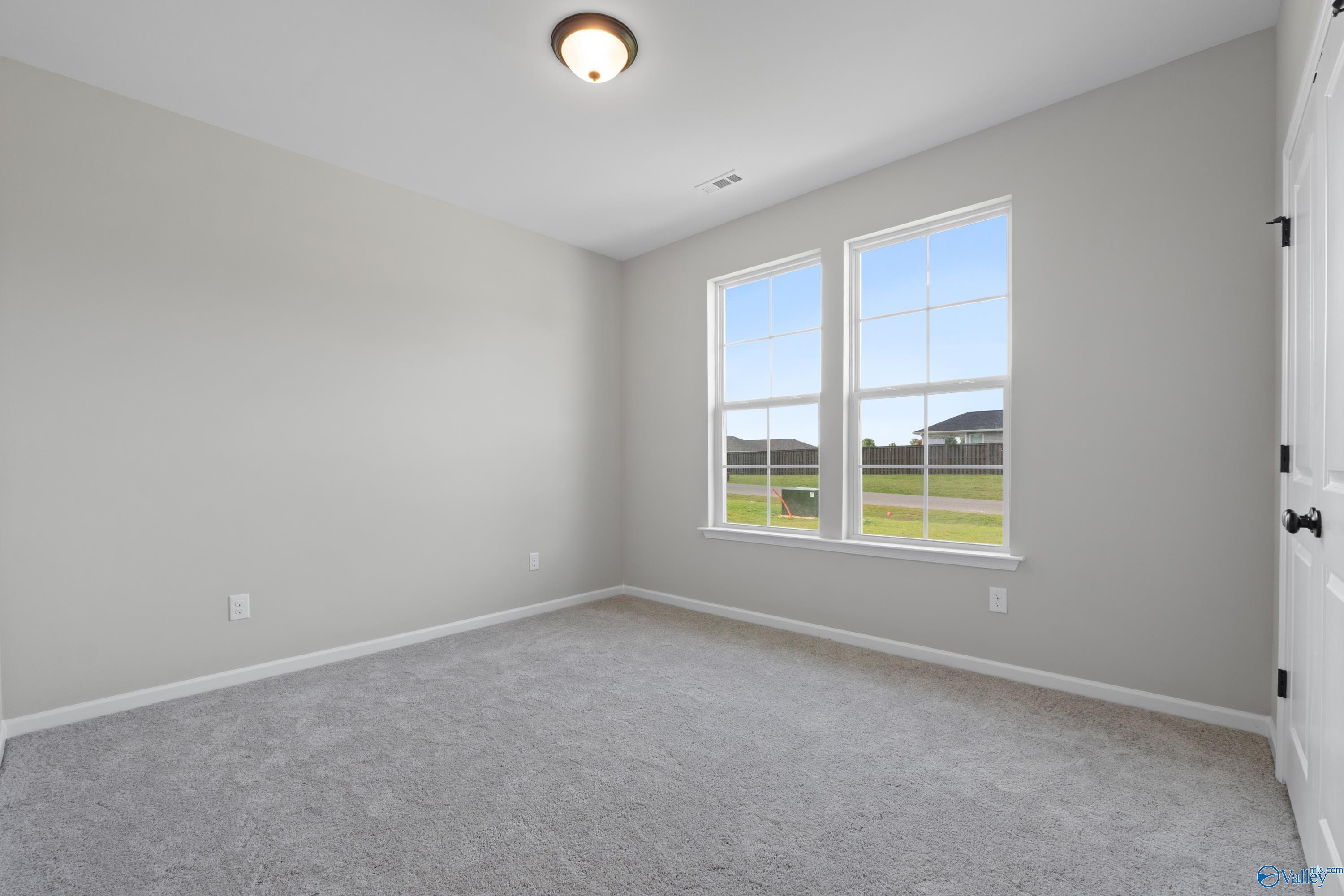 Bright secondary bedroom with large windows overlooking green yard in Davidson Homes The Phoenix, Fayetteville