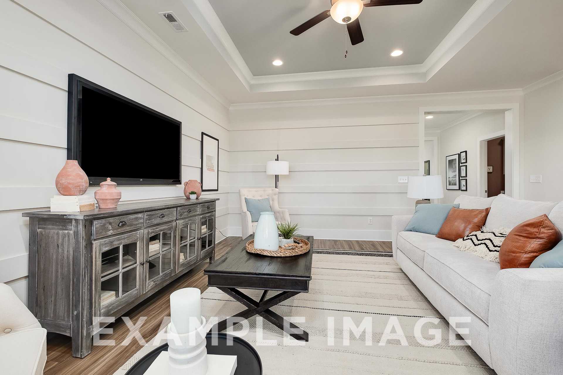 Cozy living room in The Everett B with white shiplap walls, mounted TV, white sofa, wooden credenza, and open layout