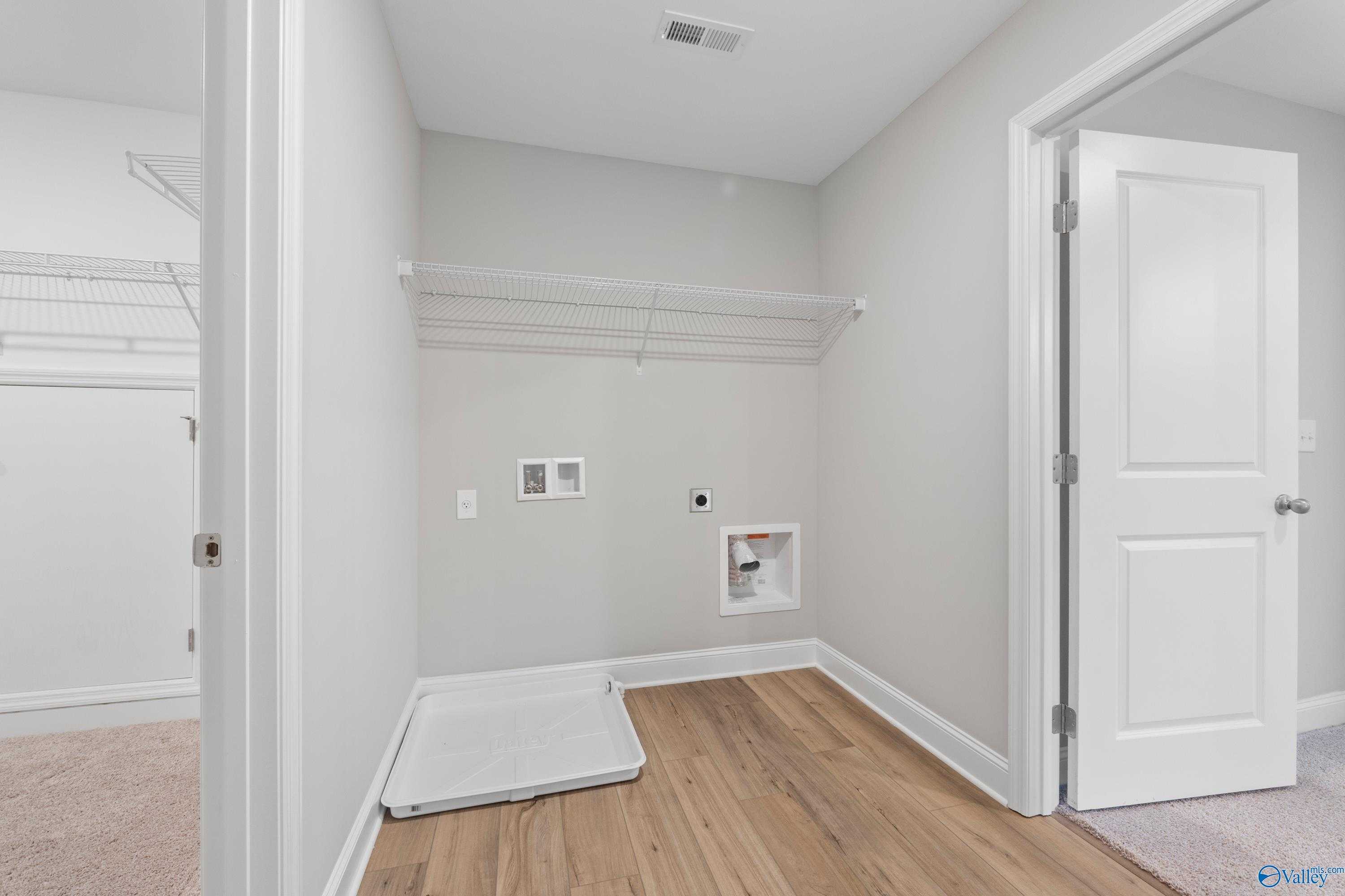 Modern laundry room with washer dryer hookups, built-in shelving, and adjacent closet in Davidson Homes Chelsea B, New Market, AL