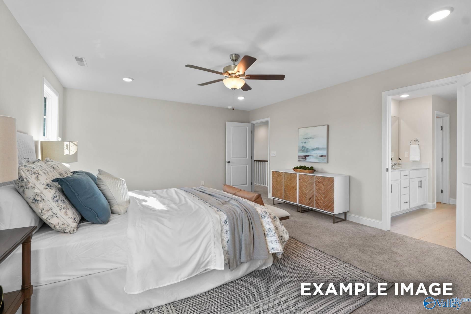 Cozy bedroom with ceiling fan, plush white bedding, and adjoining bath in Evermore Homes Madison D, Madison AL