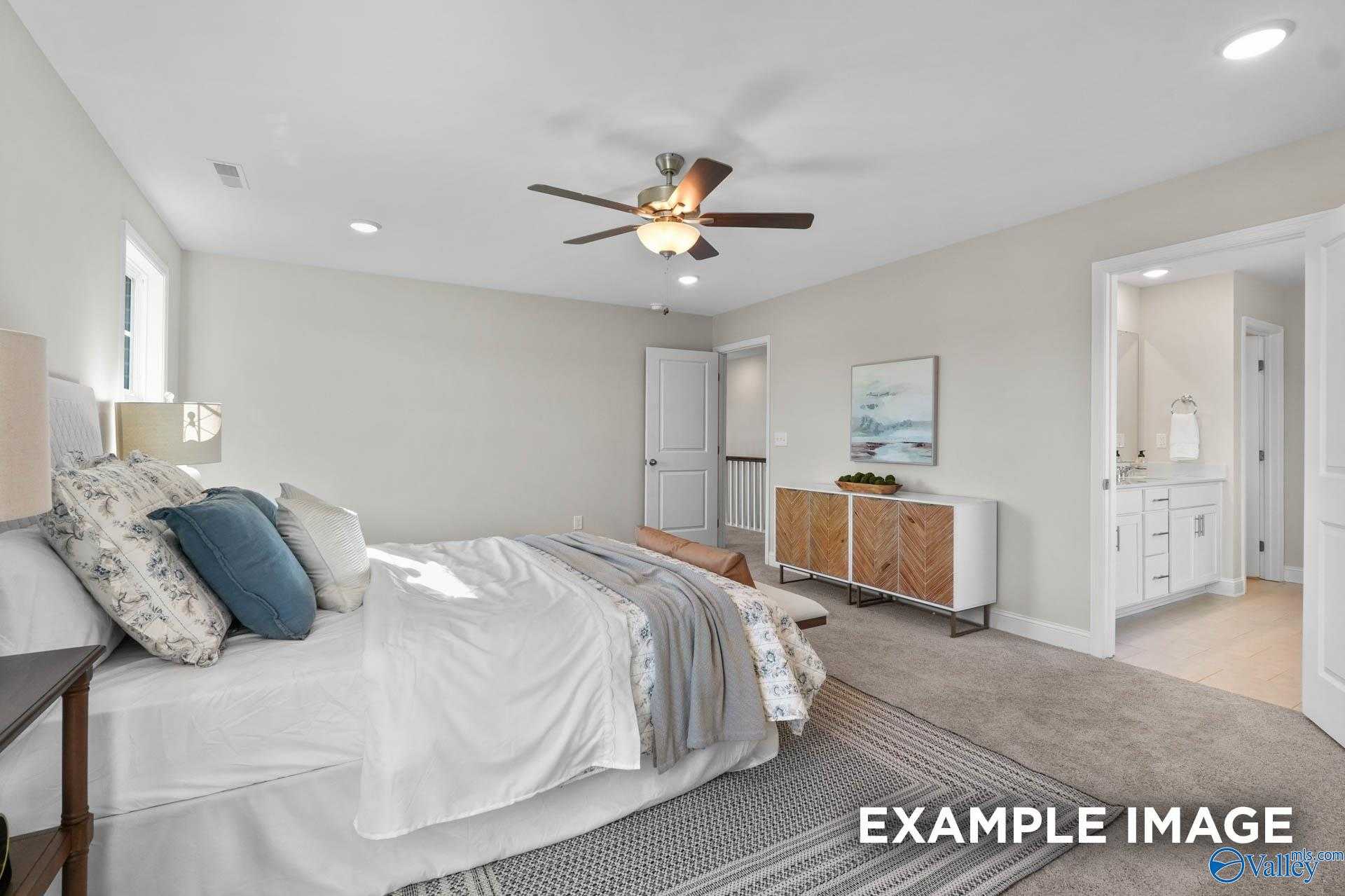 Cozy bedroom with ceiling fan, plush white bedding, and adjoining bath in Evermore Homes Madison D, Madison AL