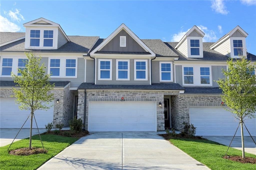 Modern 2-story townhomes with 2-car garages, gray siding, brick accents, and landscaped driveway in Hemingway, Cumming, Georgia by Davidson Homes