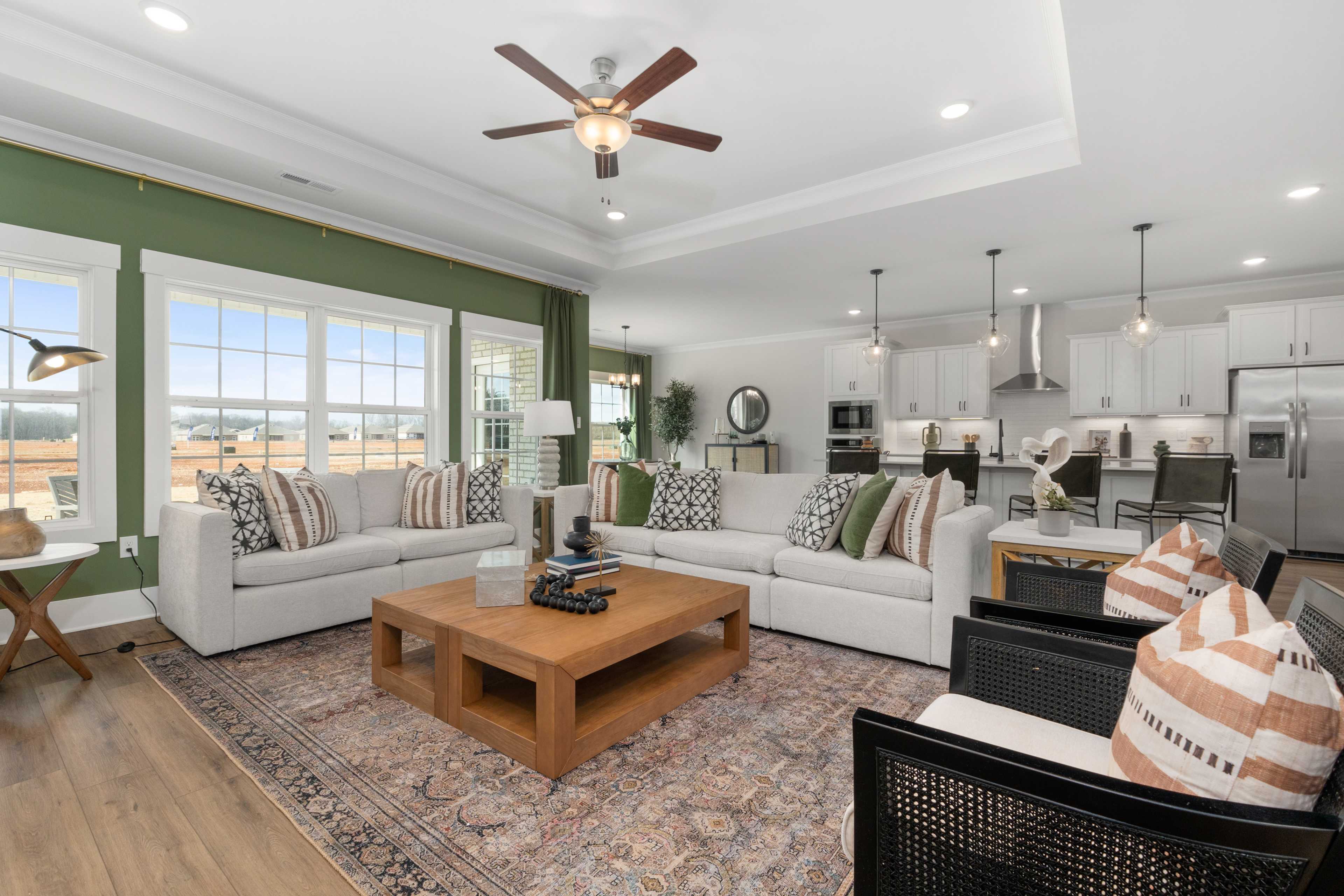 Open-concept living room and kitchen at Briercreek in Meridianville AL with white sofa, hardwood floors, and white cabinetry