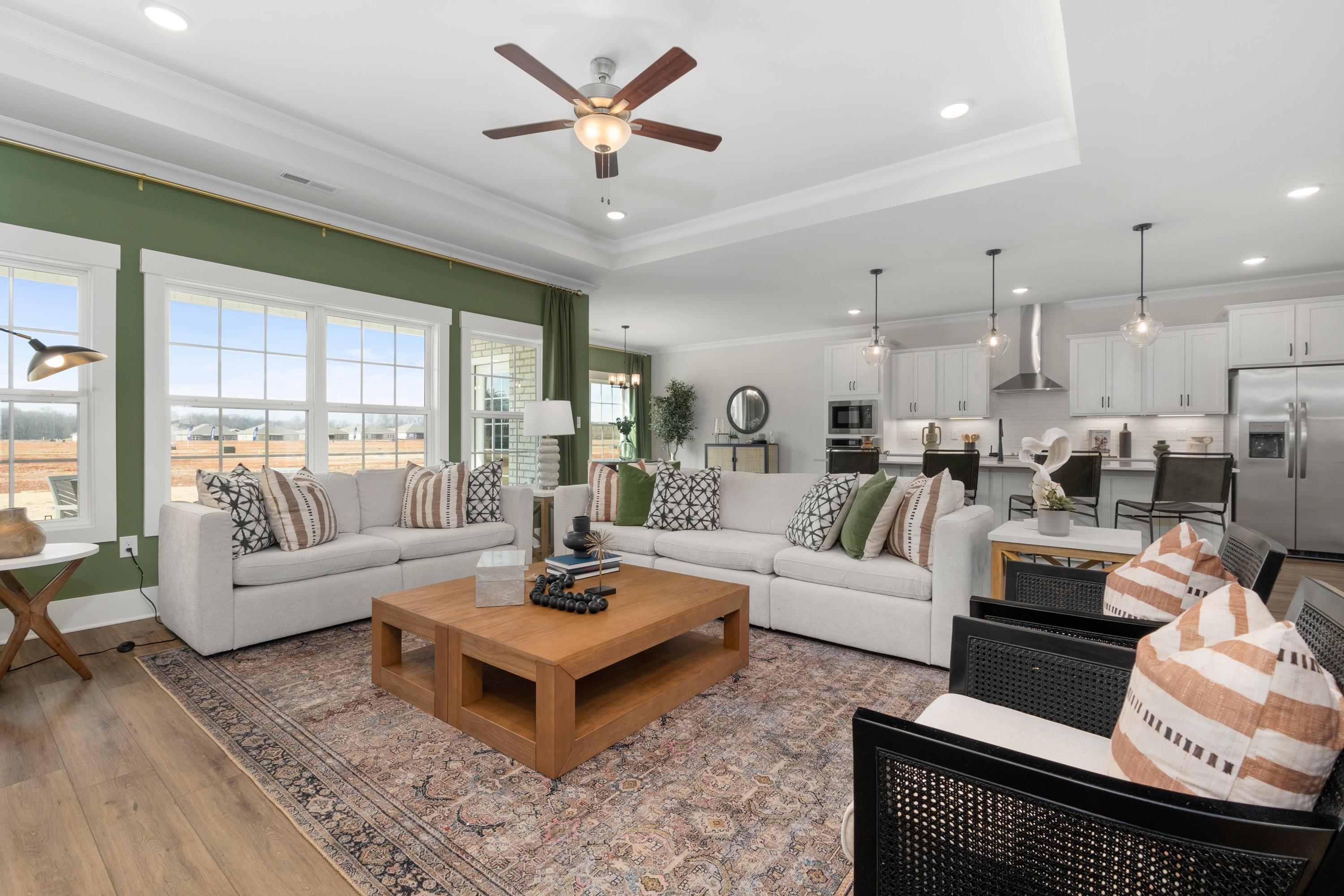 Open-concept living room and kitchen at Briercreek in Meridianville AL with white sofa, hardwood floors, and white cabinetry