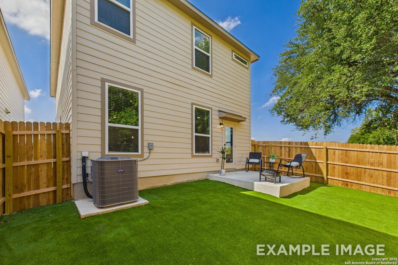Covered back patio with seating and lush green yard in 2-story Charlotte B home by Davidson Homes, San Antonio, Texas