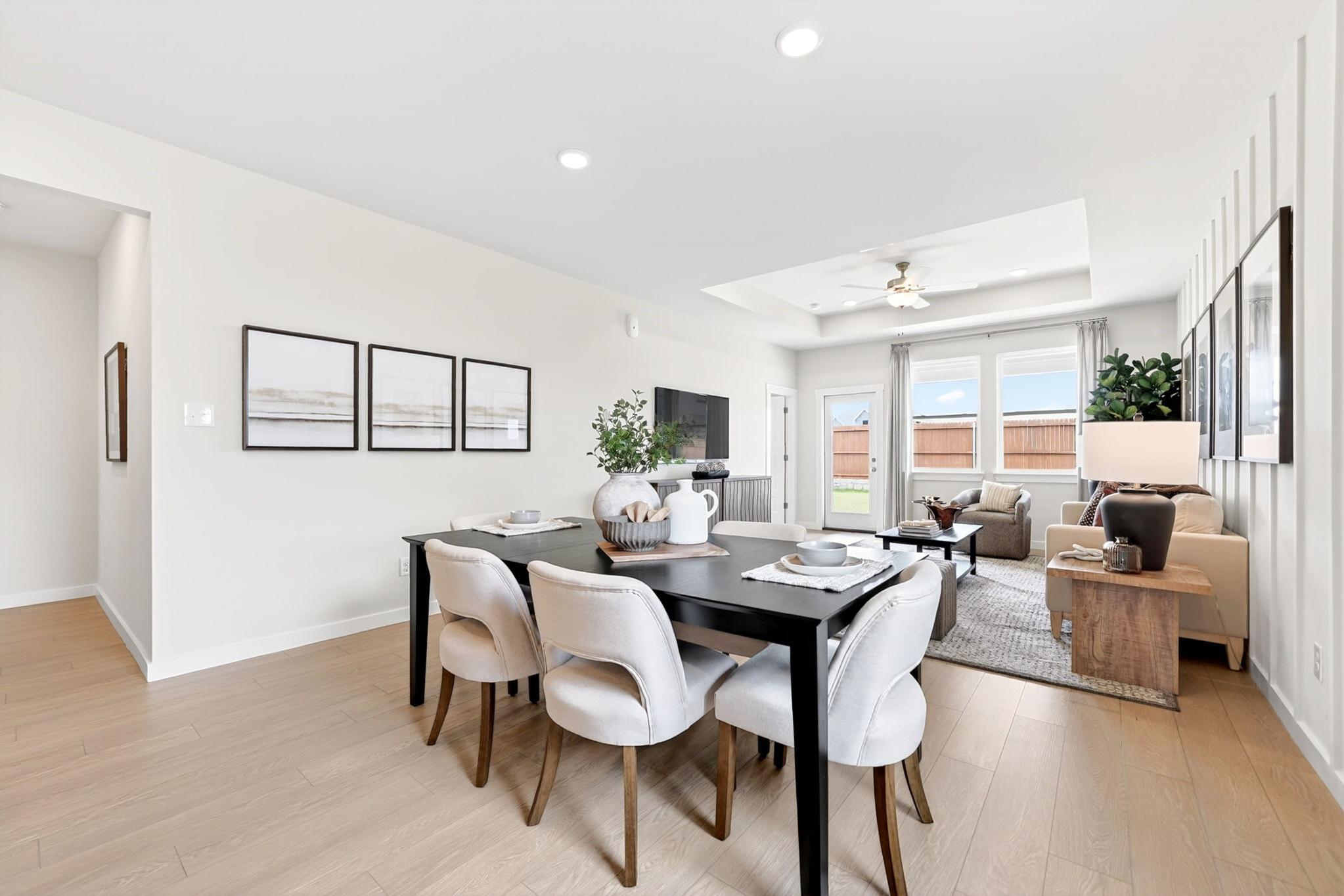 Open-concept dining and living area at Mesa Vista in San Antonio, TX by Davidson Homes with modern decor and wood floors.