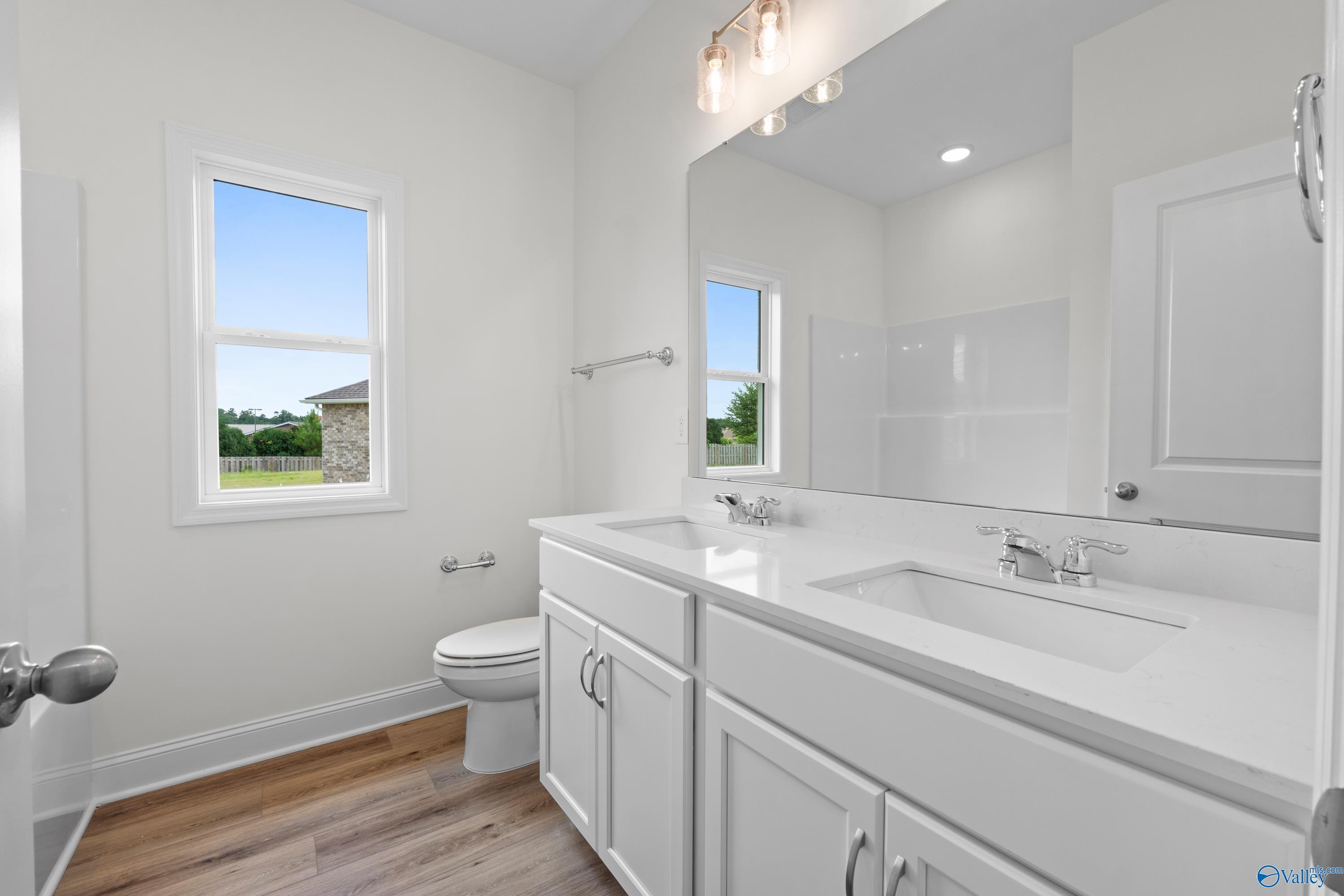 Modern bathroom with dual vanity, white cabinetry, and quartz countertops in The Everett B floor plan, Athens, Alabama.