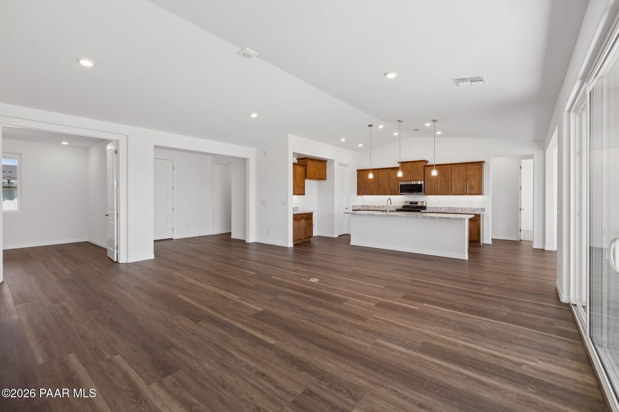 Spacious open-concept kitchen-living area with dark hardwood floors, white cabinets, large island, and sliding doors in Davidson Homes The Monarch A, Prescott, AZ