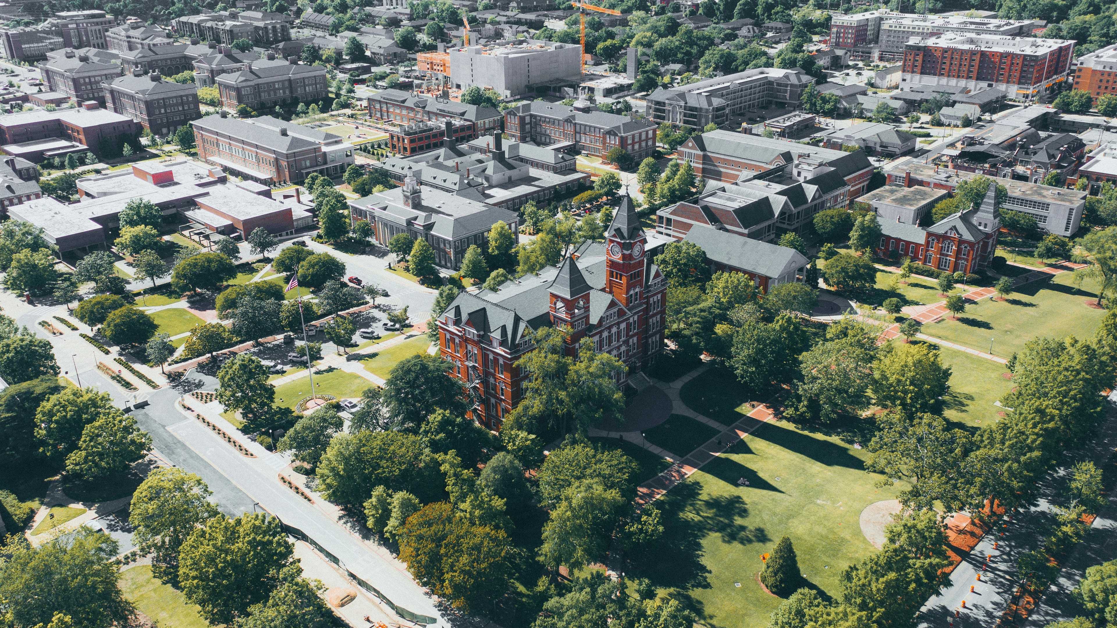 Aerial view of Auburn University campus with red brick buildings, green lawns, and surrounding neighborhoods in Auburn Region