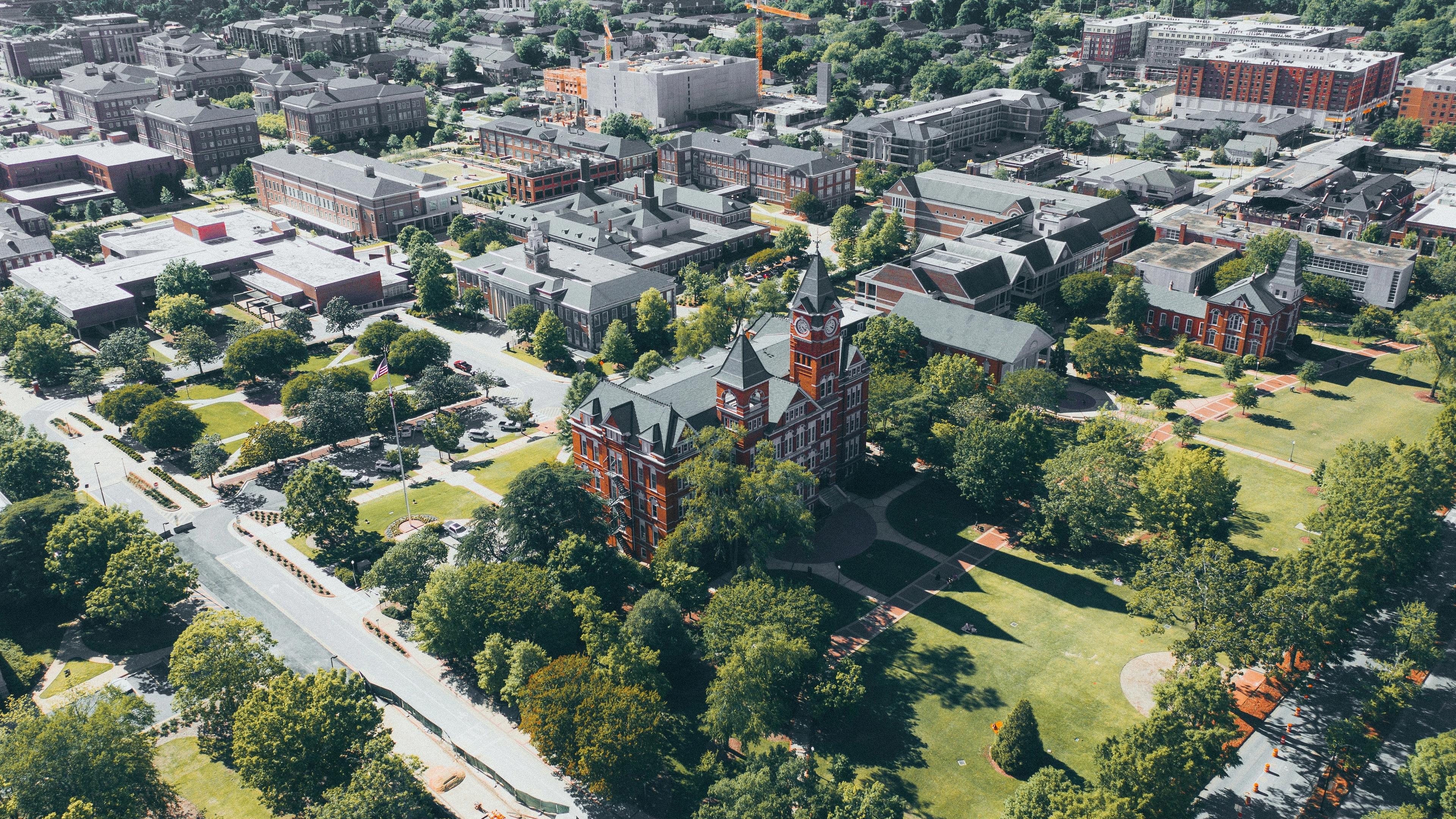Aerial view of Auburn University campus with red brick buildings, green lawns, and surrounding neighborhoods in Auburn Region