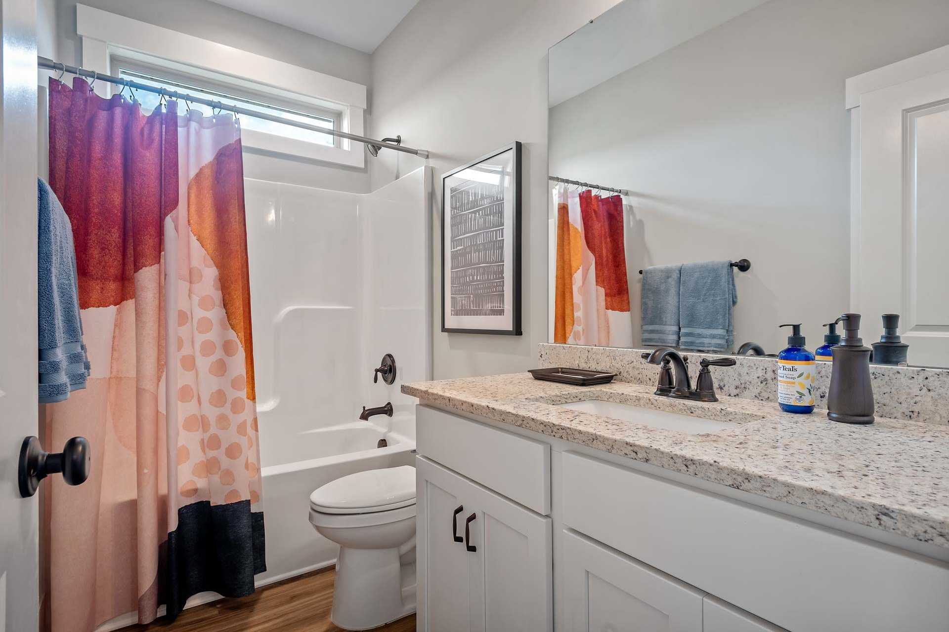 Spacious bathroom in Heritage Lakes New Market Alabama with colorful polka dot shower curtain bathtub and quartz vanity