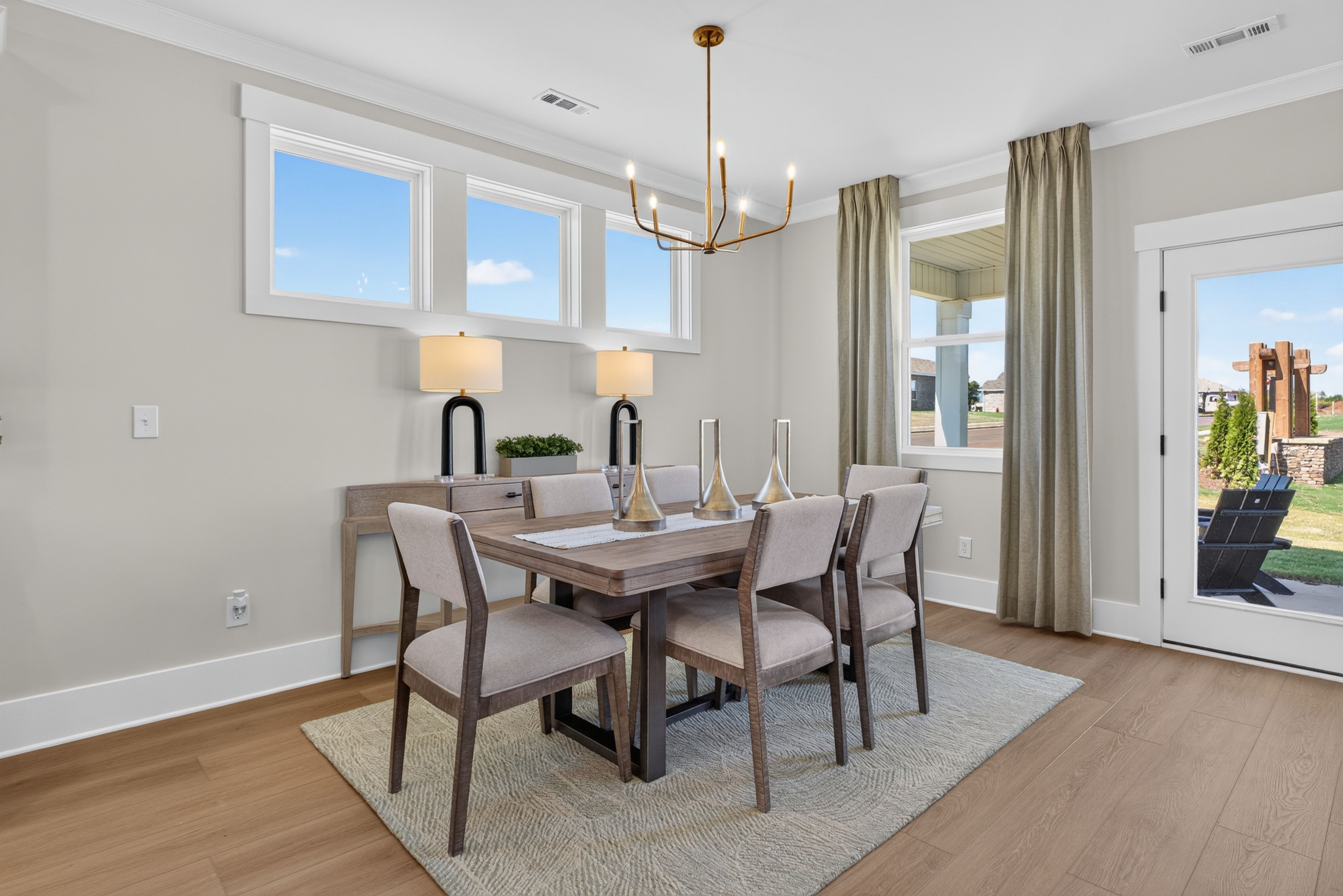 Bright dining room at Evergreen Mill in Madison, Alabama by Davidson Homes with wood table, brass chandelier, and hardwood floors