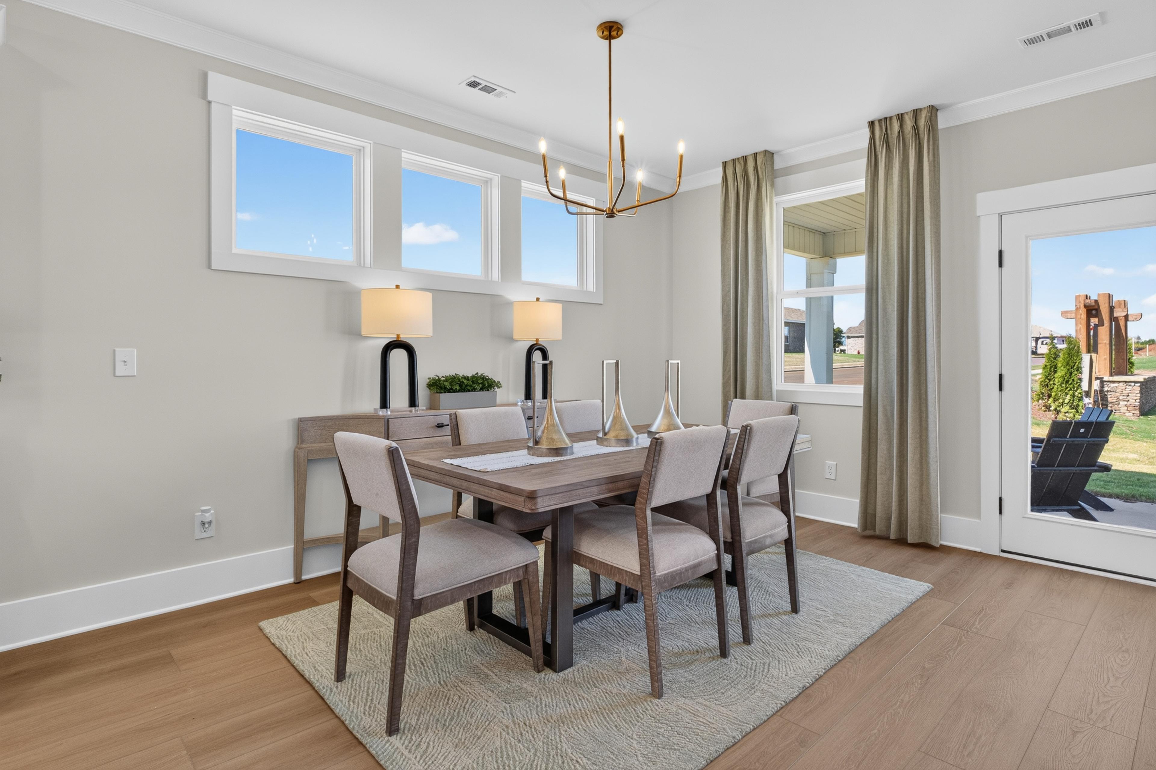 Bright dining room at Evergreen Mill in Madison, Alabama by Davidson Homes with wood table, brass chandelier, and hardwood floors
