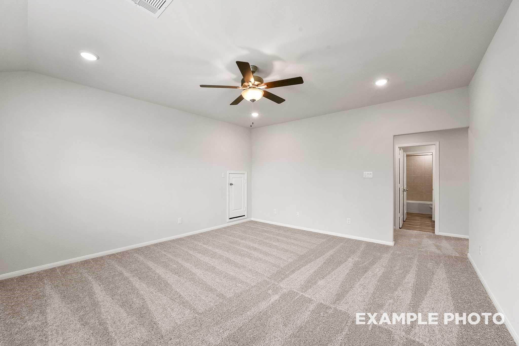 Spacious master bedroom with ceiling fan, beige carpet, walk-in closet, and en-suite bath in Davidson Homes Tierra B, Beasley TX