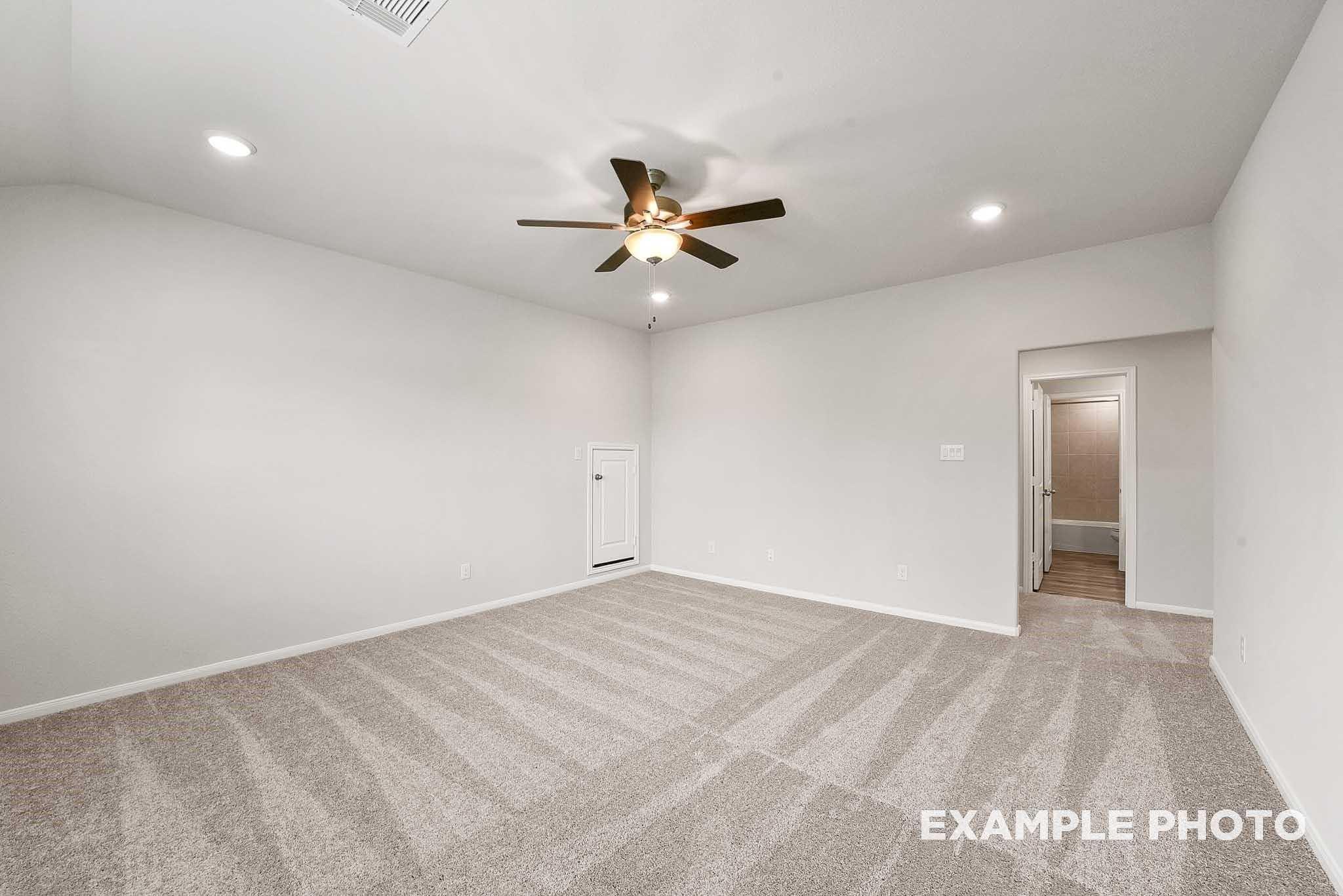 Spacious master bedroom with ceiling fan, beige carpet, walk-in closet, and en-suite bath in Davidson Homes Tierra B, Beasley TX
