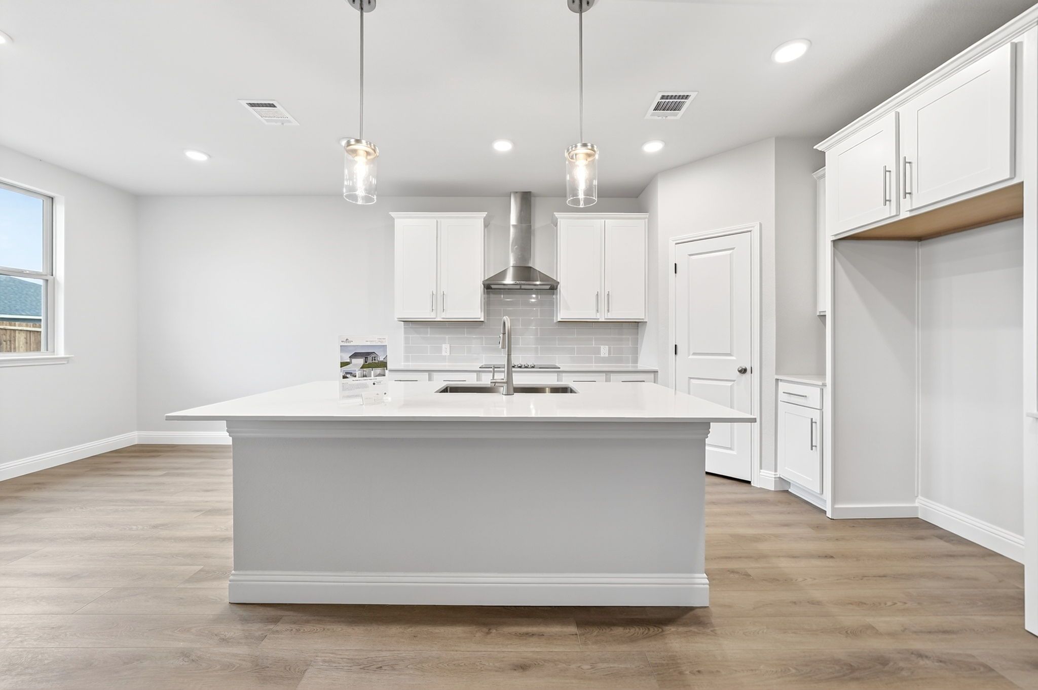 Modern kitchen in The Redbud featuring a large center island, white cabinetry, and stainless steel appliances.