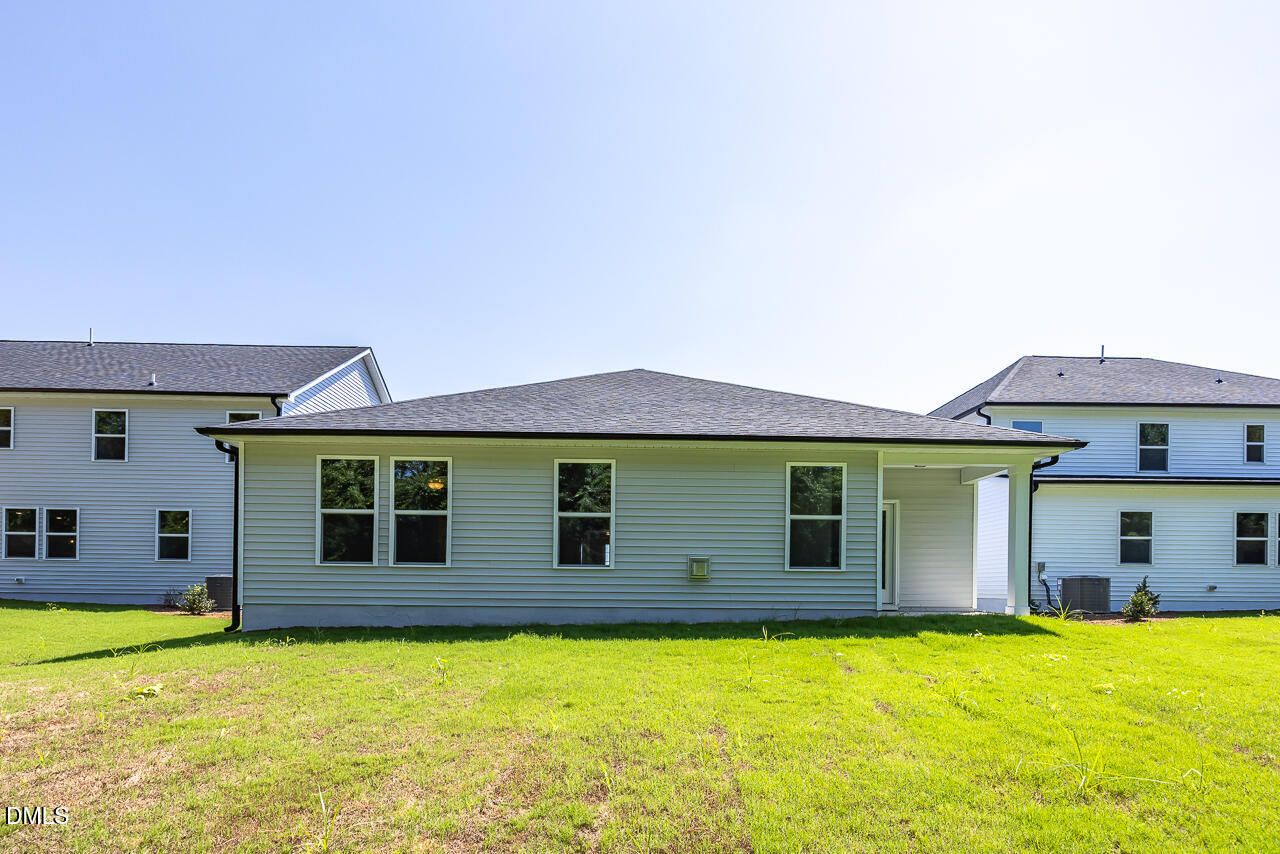 Rear exterior of single-story The Daphne D by Davidson Homes with covered patio and spacious backyard in Woodland Crossing, Zebulon NC