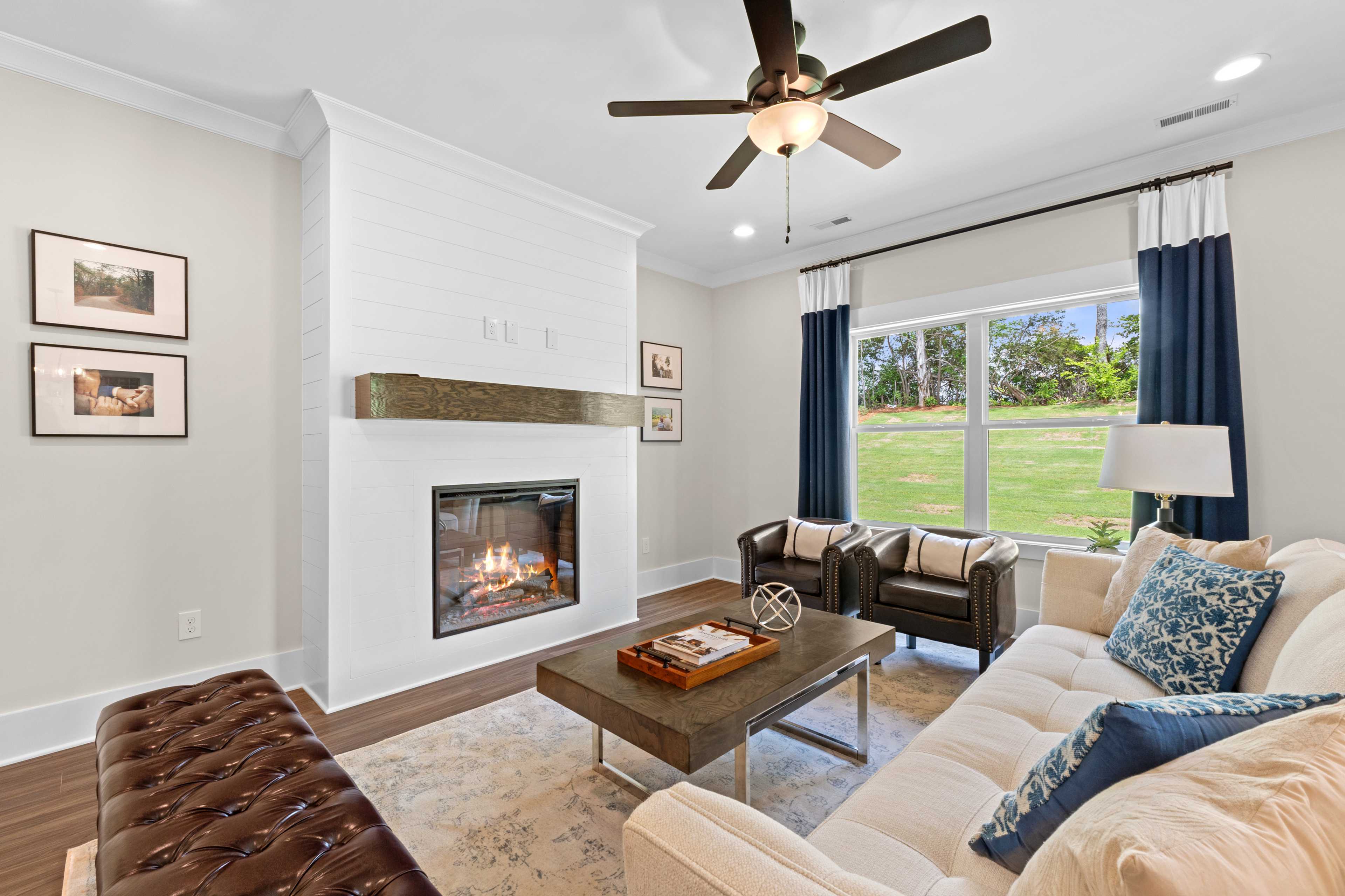 Cozy living room at Ivy Hills in Toney Alabama with gas fireplace, hardwood floors, and large windows overlooking lawn