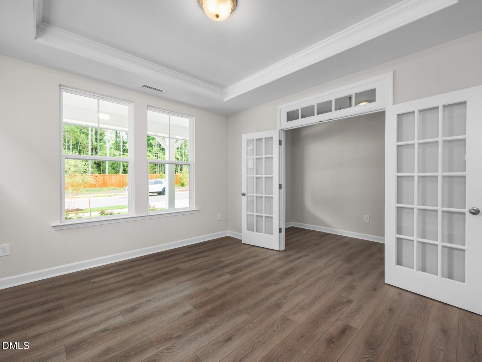 Bright living room with hardwood floors, large windows to wooded backyard, open French doors in Davidson Homes The Aspen, Wake Forest, NC