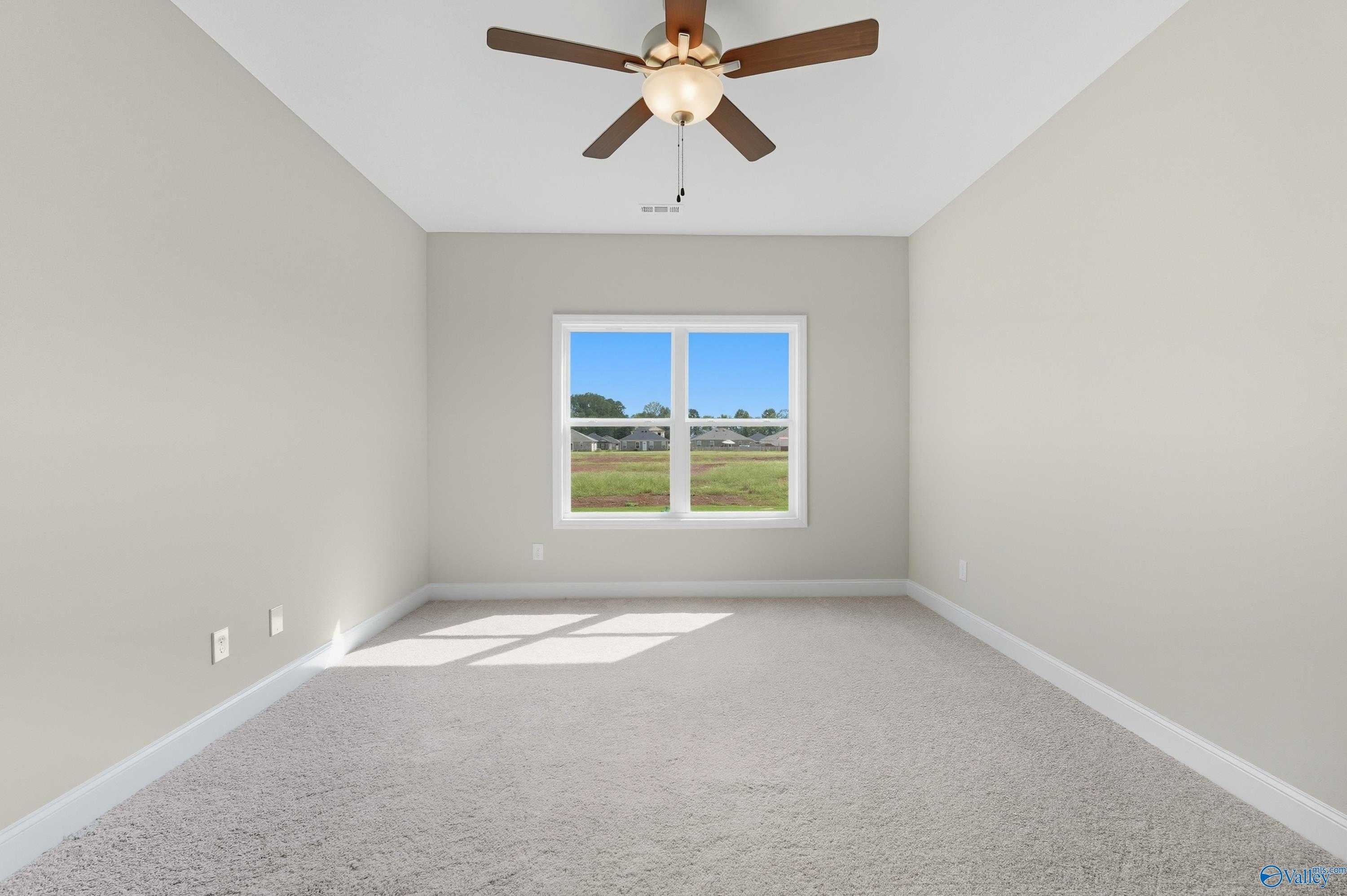 Bright secondary bedroom with ceiling fan, carpeted floor, and large window in Davidson Homes The Franklin, Meridianville, Alabama