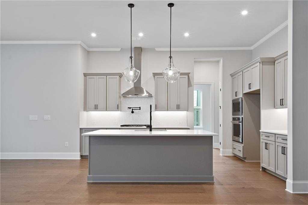 Modern gray shaker kitchen with large island, stainless hood, pendant lights in Davidson Homes Seaside B, Woodstock GA