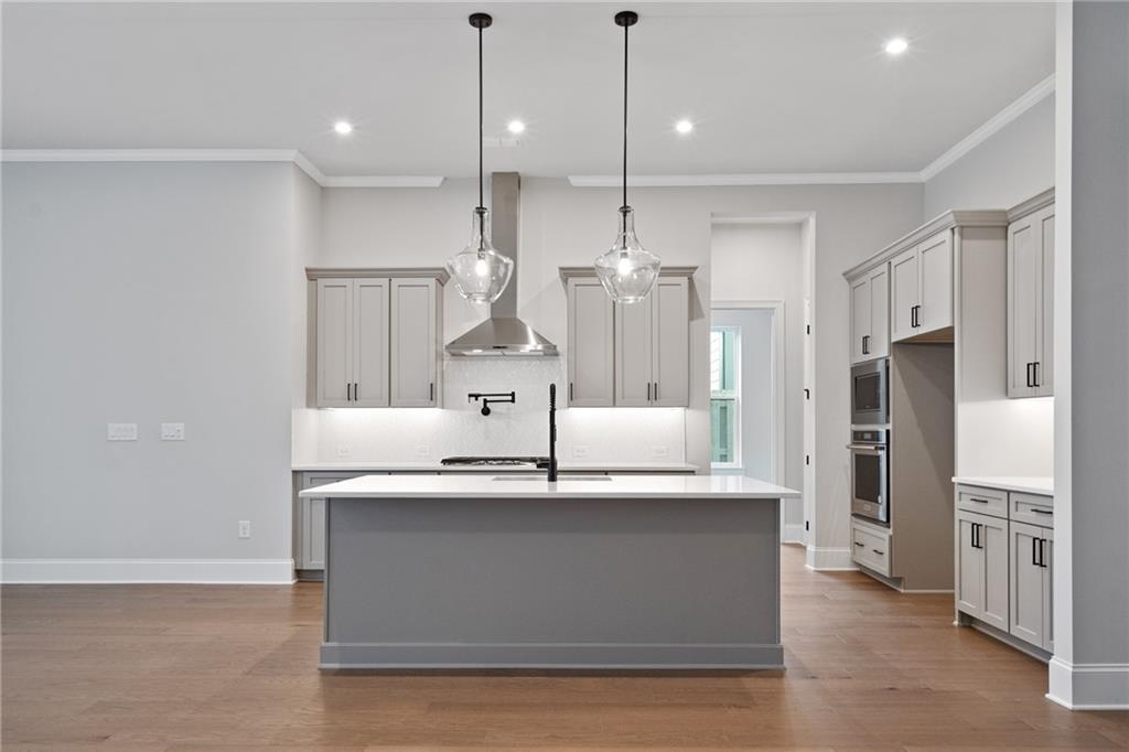 Modern gray shaker kitchen with large island, stainless hood, pendant lights in Davidson Homes Seaside B, Woodstock GA