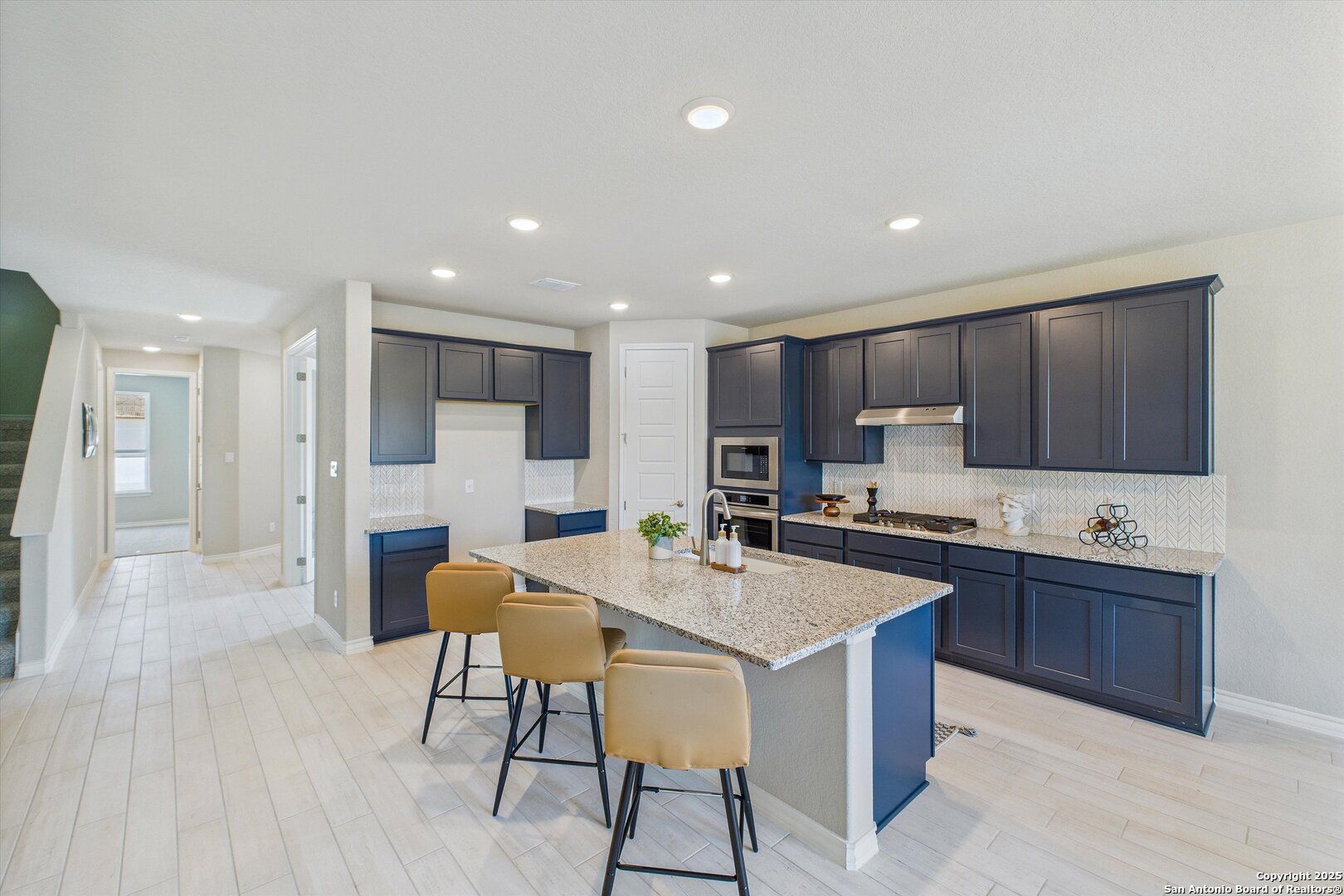 Open-concept kitchen with navy cabinets, quartz island, stainless appliances in The Jennings H by Davidson Homes, Ladera, San Antonio