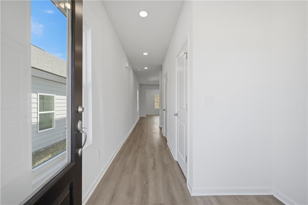 Bright entry hallway with hardwood floors and glass-panel front door in Davidson Homes' The Russell B, The Bluffs, Canton, GA