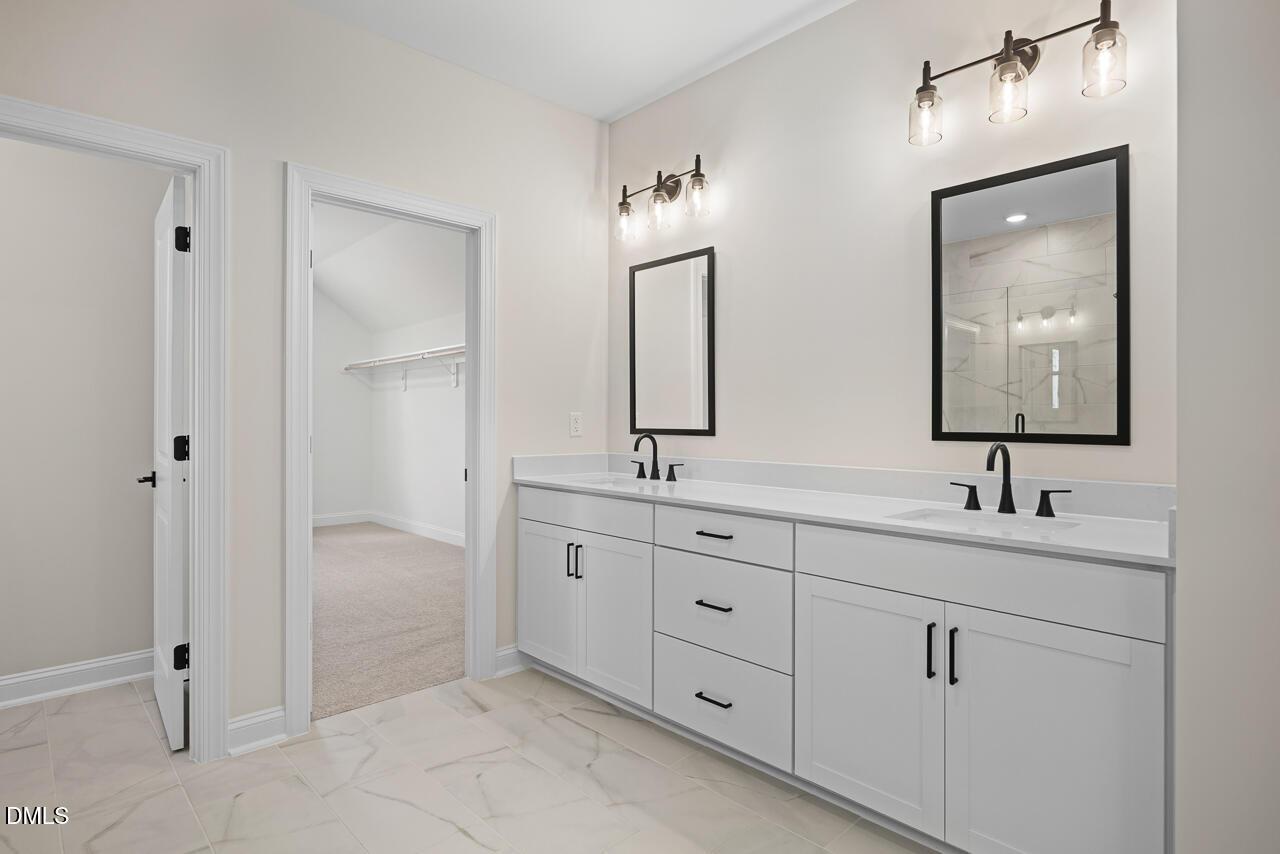 Dual vanity bathroom with white cabinetry, black fixtures, and marble tile in Davidson Homes The Crawford D, Wake Forest, NC
