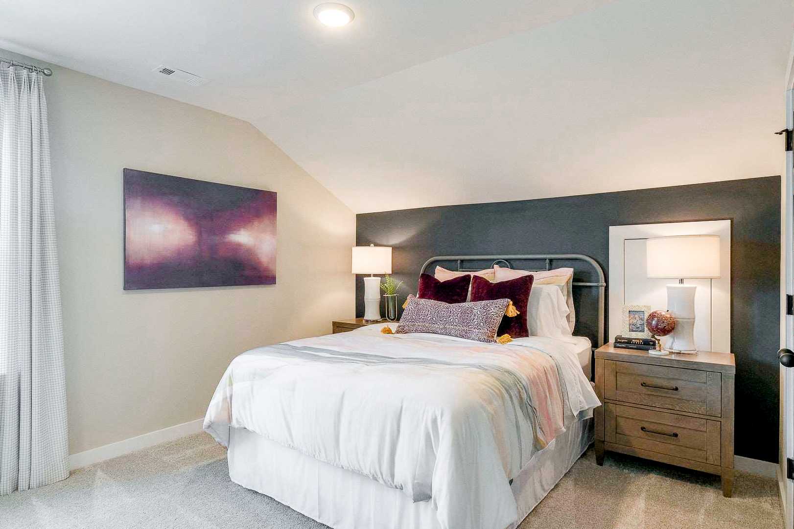 Cozy bedroom with white bed, plush pillows, abstract art, and gray accent wall at The Meadows in Smyrna TN by Davidson Homes