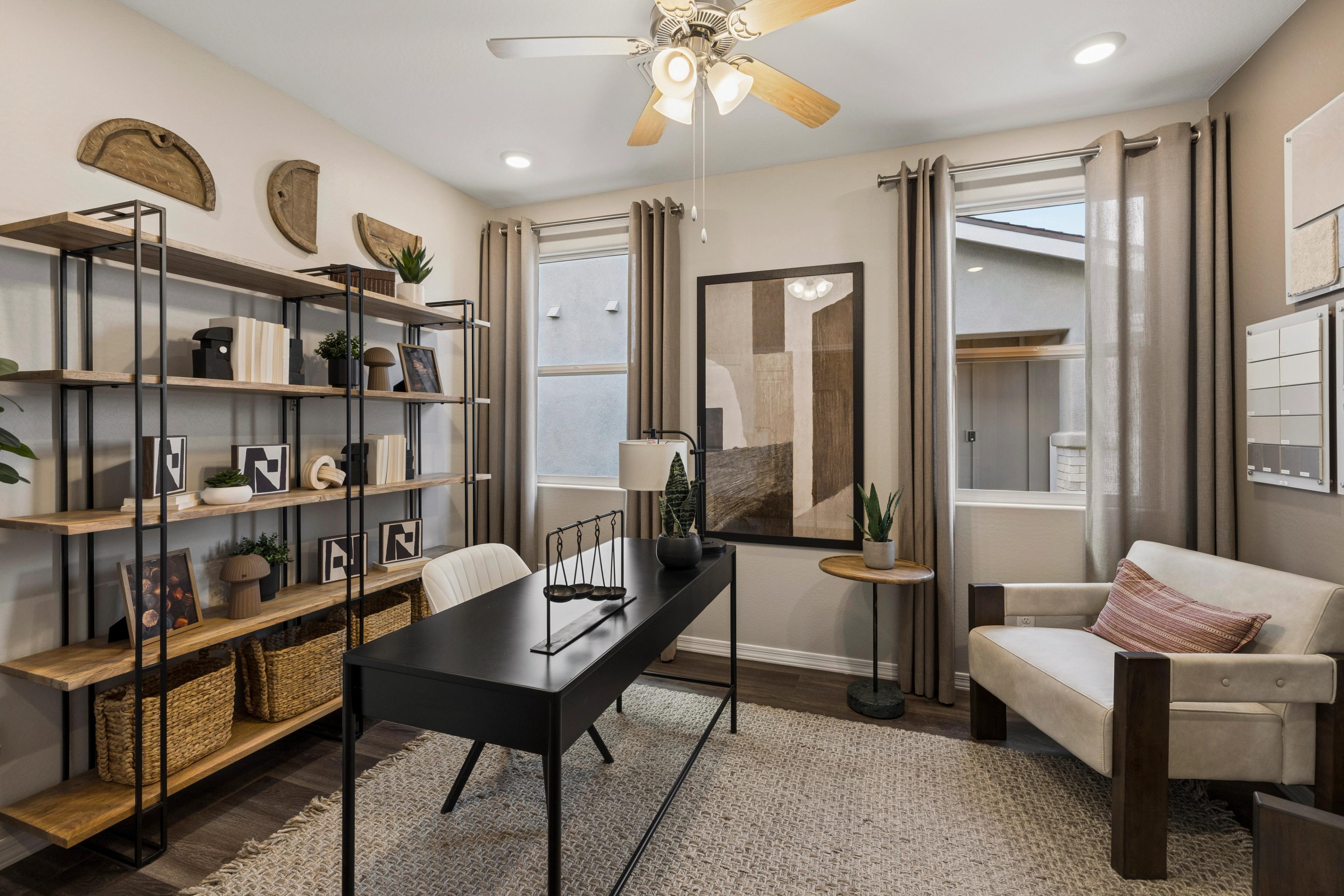 Modern home office at Senator Cottages in Prescott AZ with black desk, wooden bookshelves, potted plants, and ceiling fan