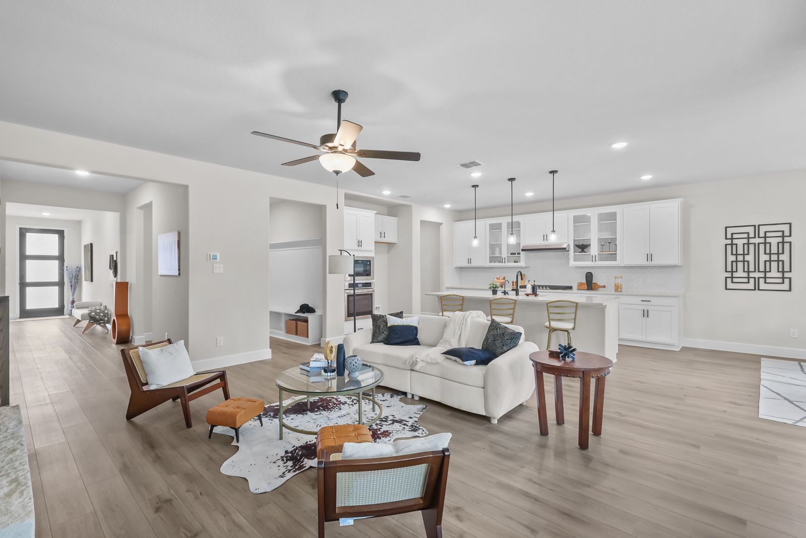Open-concept living room and gourmet kitchen in The Belmont featuring white cabinetry and spacious modern design.