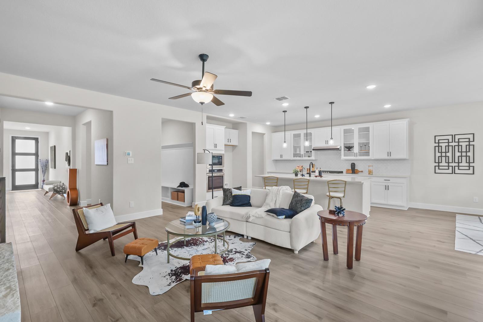 Open-concept living room and gourmet kitchen in The Belmont featuring white cabinetry and spacious modern design.