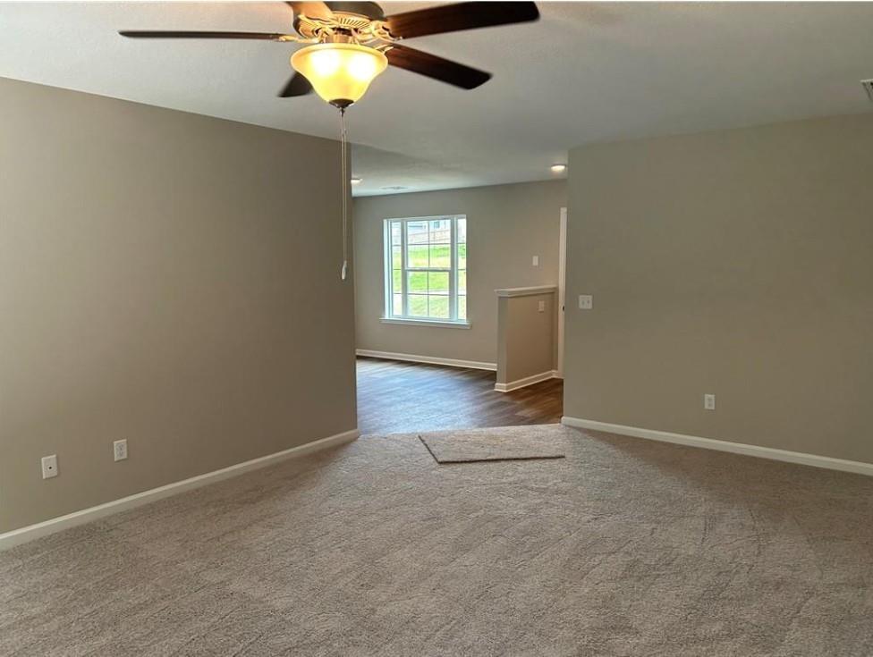 Spacious empty bedroom with ceiling fan, large window, neutral beige walls, and open doorway in Davidson Homes The Washington, Phenix City