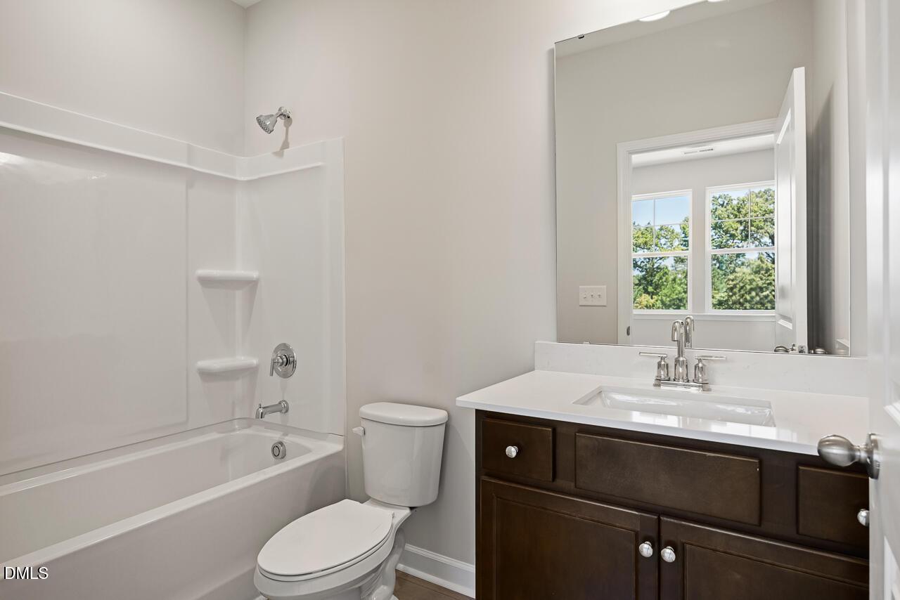 Modern bathroom with white tub-shower combo and dark wood vanity in The Chestnut floor plan, Montrose, Aberdeen, NC.