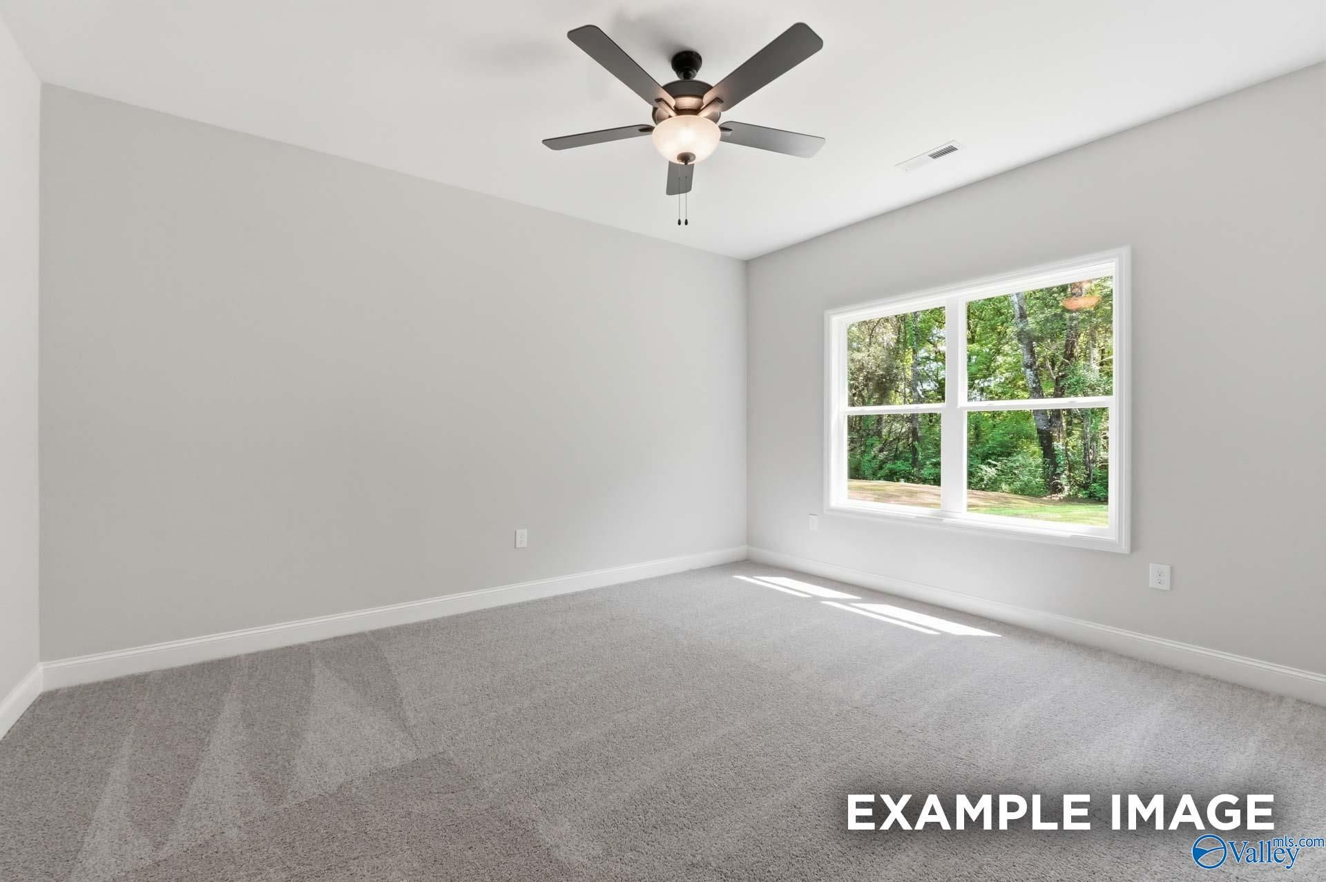 Bright bedroom with neutral carpet and ceiling fan in The Franklin C floor plan at The Highlands, Arab, Alabama.