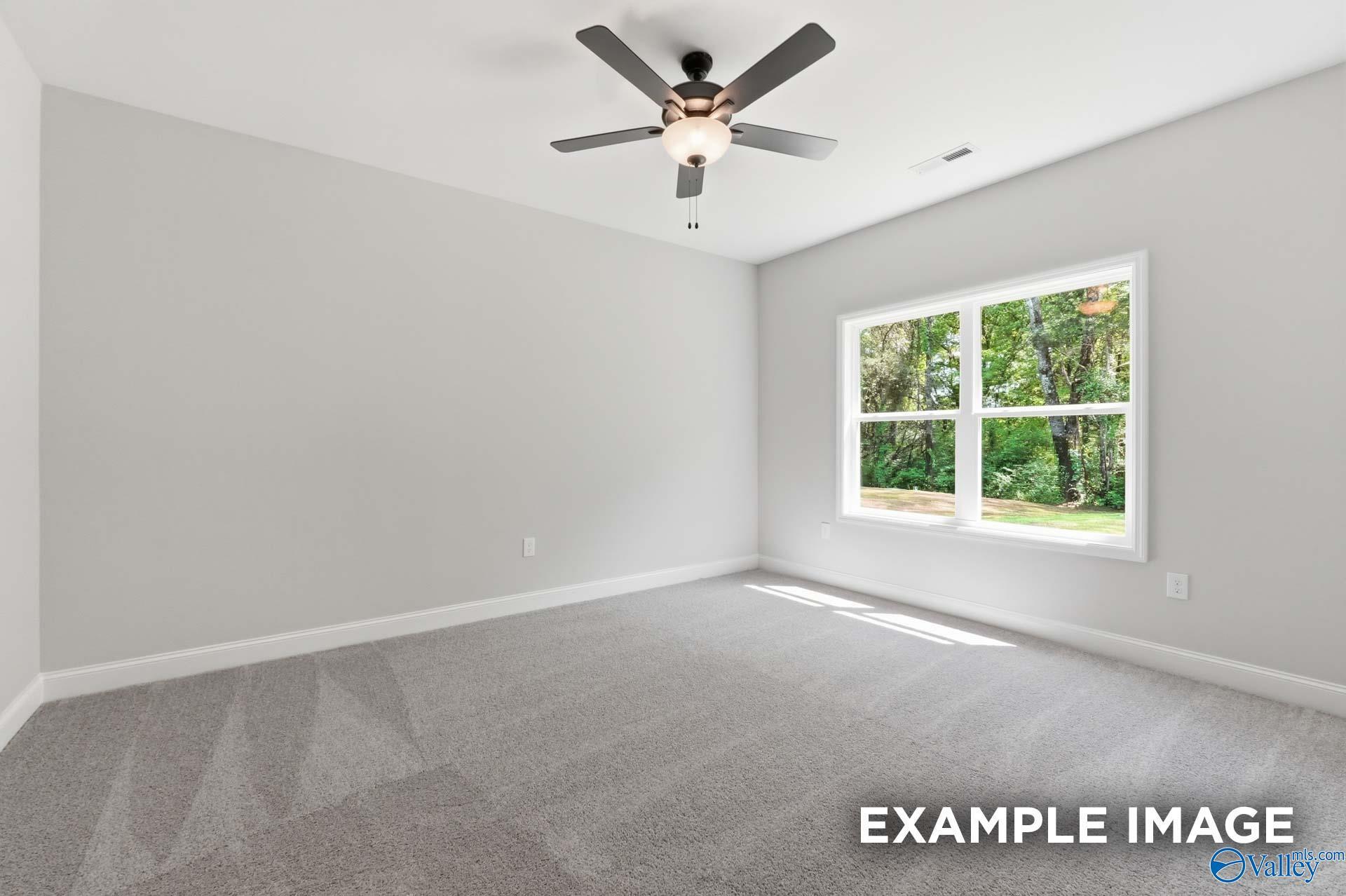 Bright bedroom with neutral carpet and ceiling fan in The Franklin C floor plan at The Highlands, Arab, Alabama.
