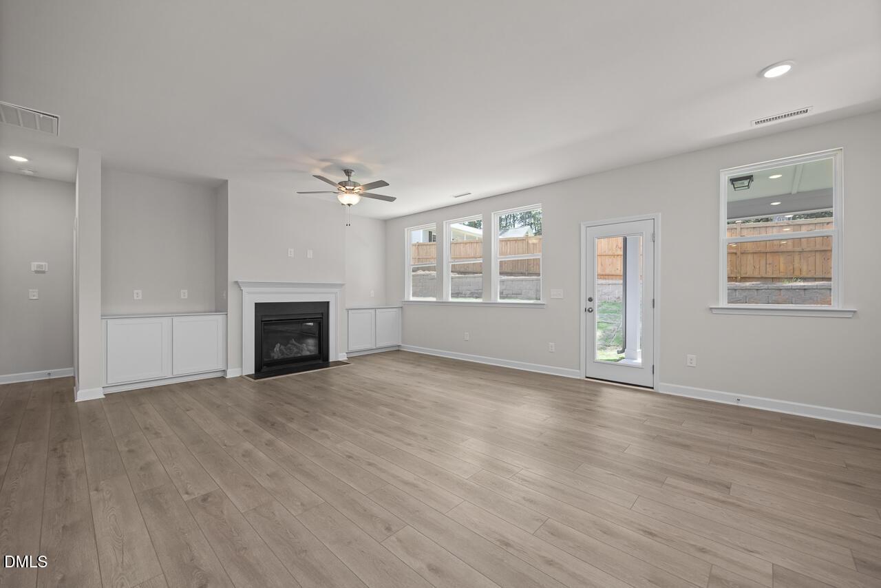 Spacious living room with fireplace and wood flooring in The Ashport G floor plan at Sage on North Main, Wake Forest, NC.