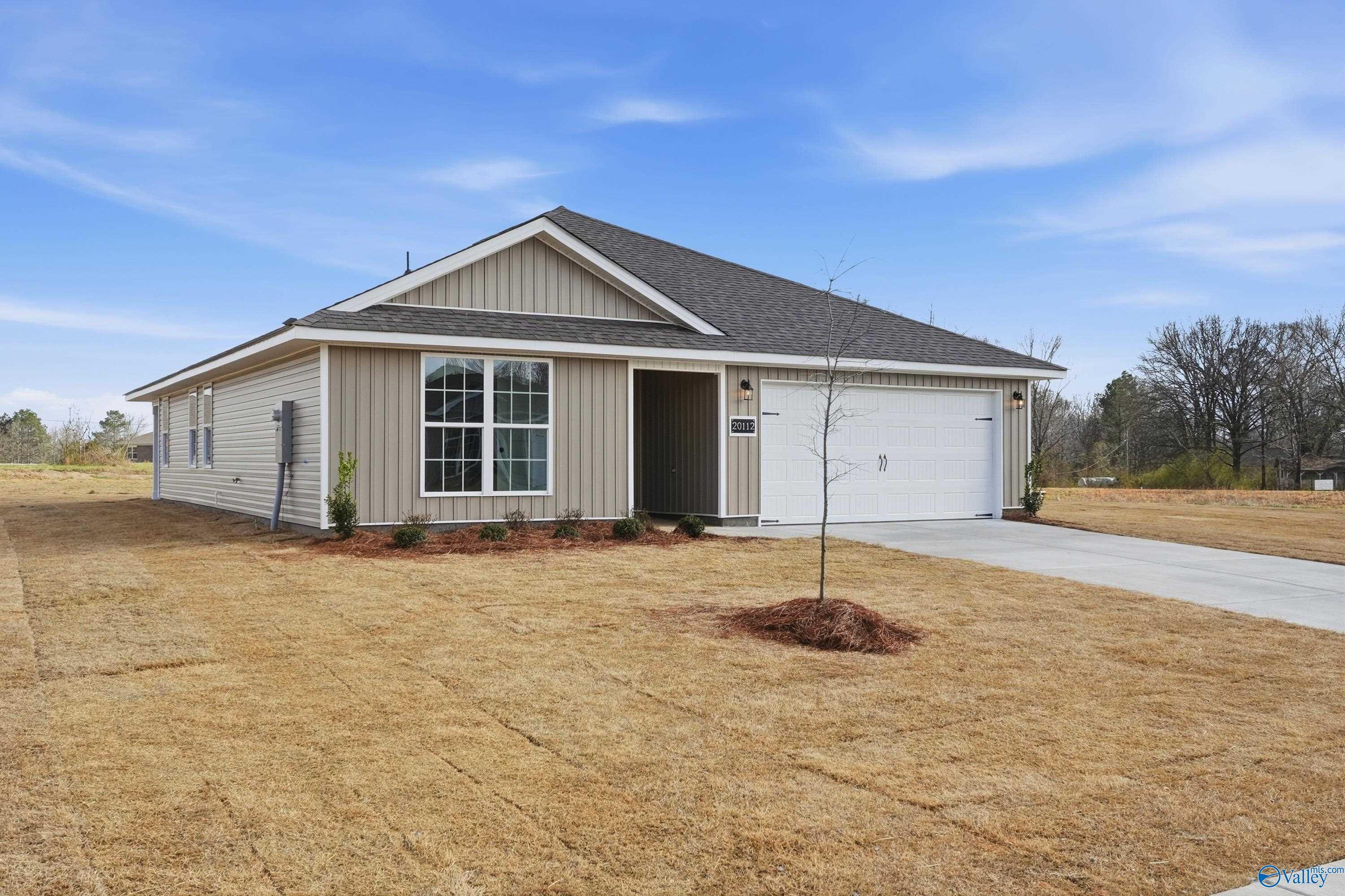 Tan single-story 3-bedroom home with gabled roof, large windows, two-car garage, driveway, and sparse landscaping in Chapel Hill, Athens, Alabama