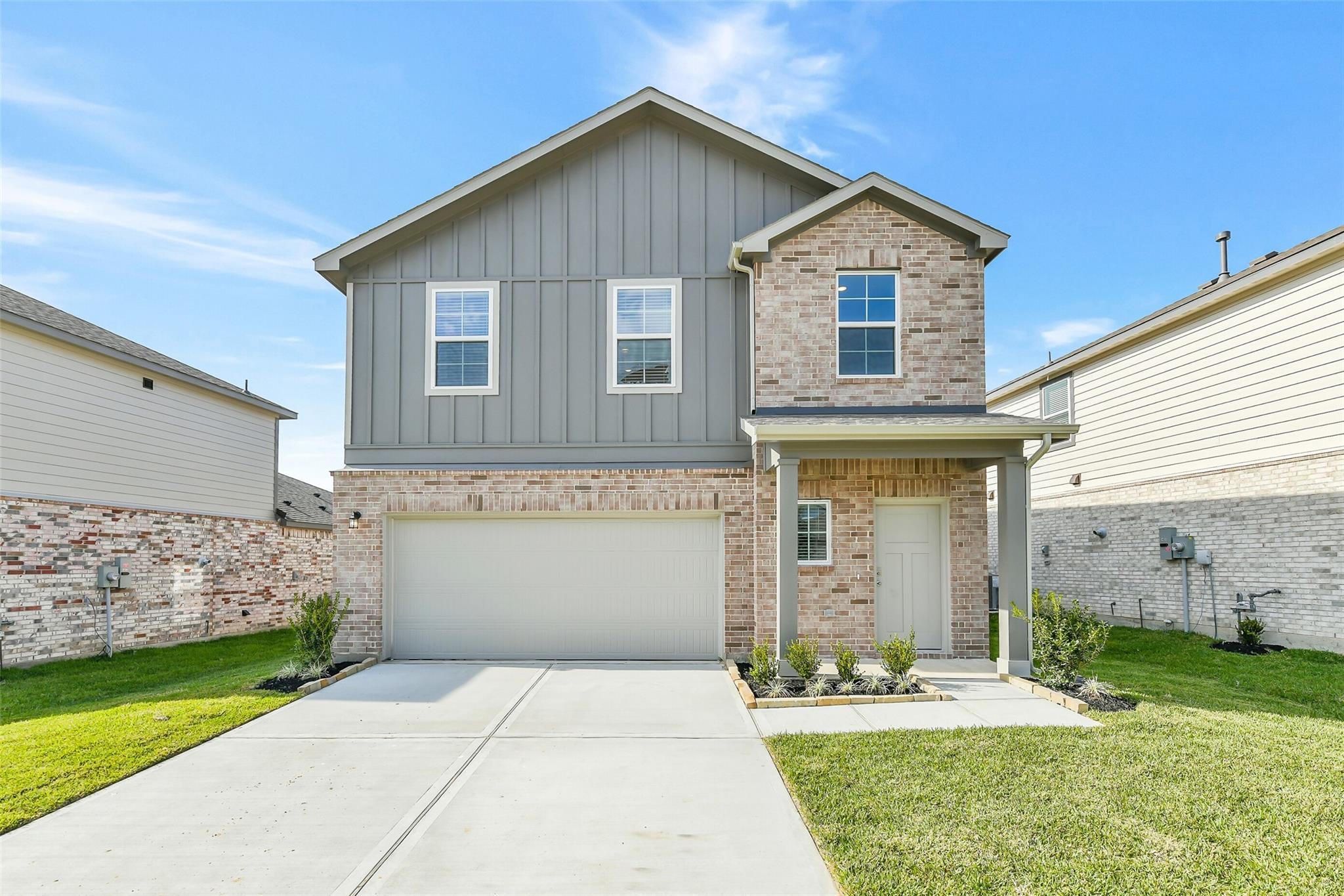 Modern 2-story gray-sided home with brick accents, 2-car garage, and covered porch in Lakes at Black Oak, Magnolia, Texas