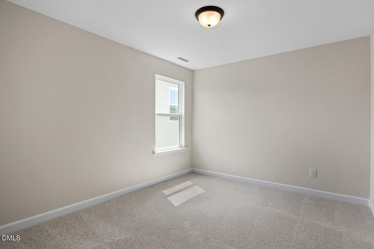 Bright empty bedroom with neutral walls, carpet, and window in Davidson Homes The Birch II C, Sage on North Main, Wake Forest, NC