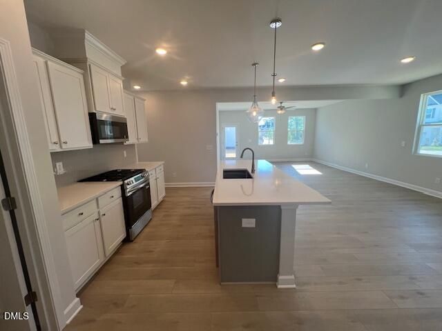Open-concept kitchen with white shaker cabinets, quartz island sink, stainless steel appliances in Davidson Homes Adalynn B, Lillington, NC