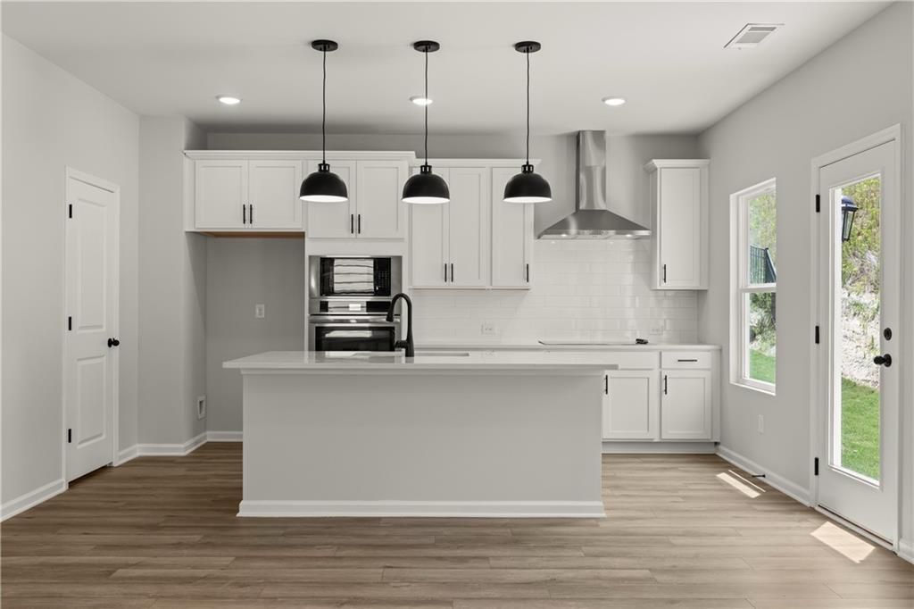 Modern white kitchen with island, pendant lighting, and stainless appliances in The Hartwell A plan at The Bluffs, Canton.