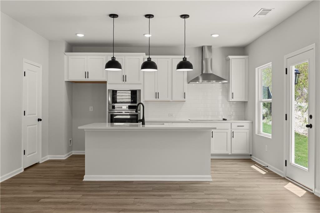 Modern kitchen with white cabinets, island, and stainless steel appliances in The Hartwell B plan at The Bluffs, Canton.
