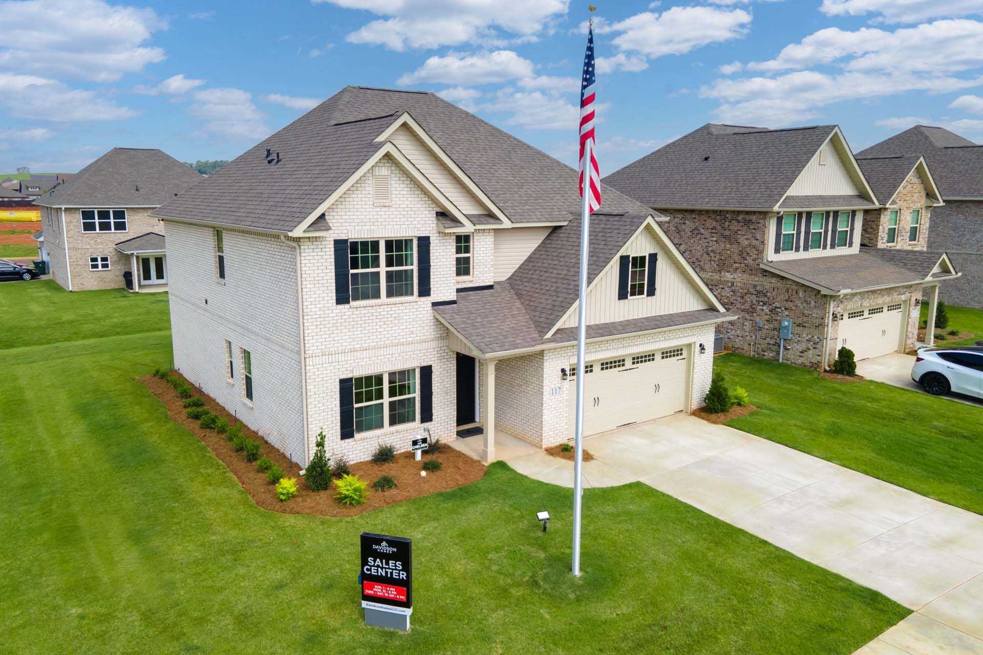 Brick home exterior at Walker's Hill in Meridianville, Alabama with American flag, Davidson Homes sale sign, and green lawn