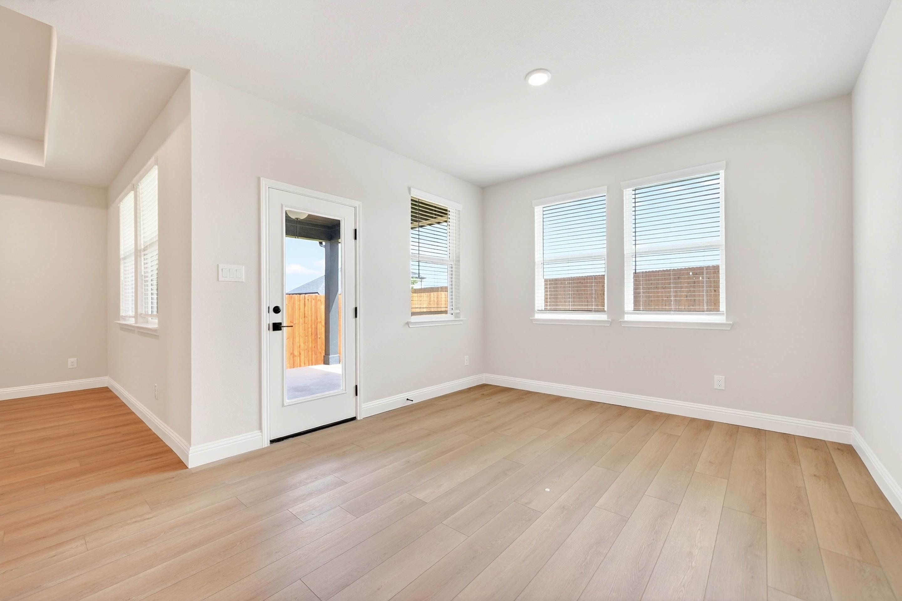 Bright open-concept living area in The Holly by Davidson Homes featuring light wood flooring and access to back patio.
