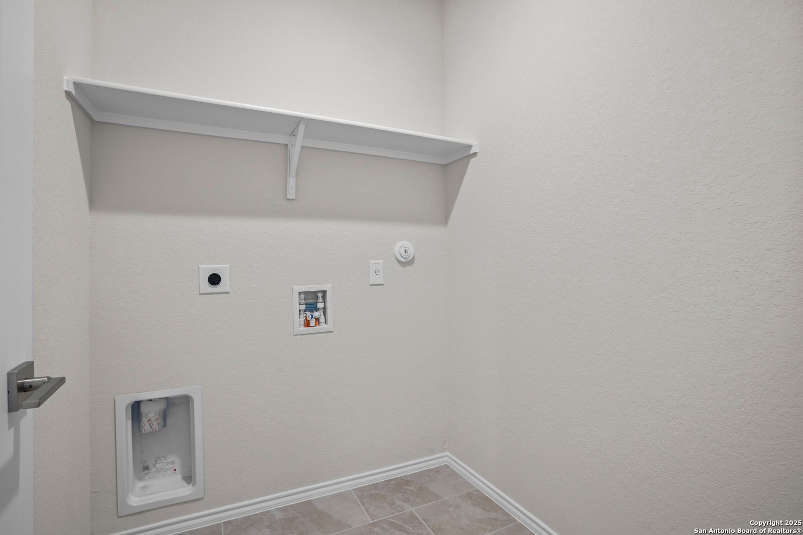 Modern laundry room with utility sink, washer/dryer hookups, and built-in shelves in The Asheville J by Davidson Homes, San Antonio