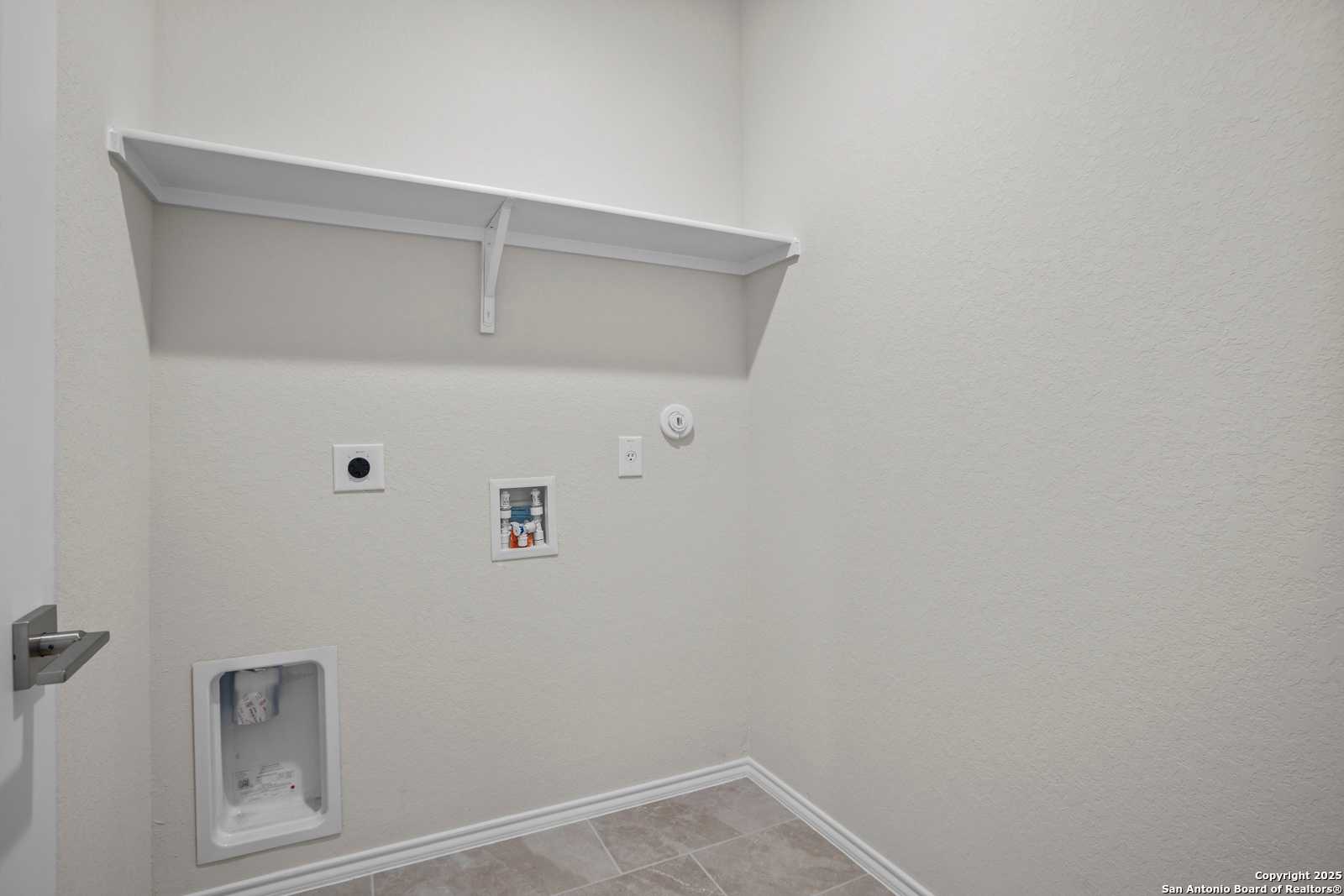 Modern laundry room with utility sink, washer/dryer hookups, and built-in shelves in The Asheville J by Davidson Homes, San Antonio