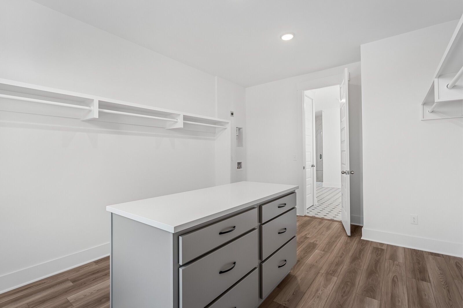 Spacious walk-in closet with built-in white shelving, hanging rods, and central island dresser in Davidson Homes The Alston A, Murfreesboro, TN